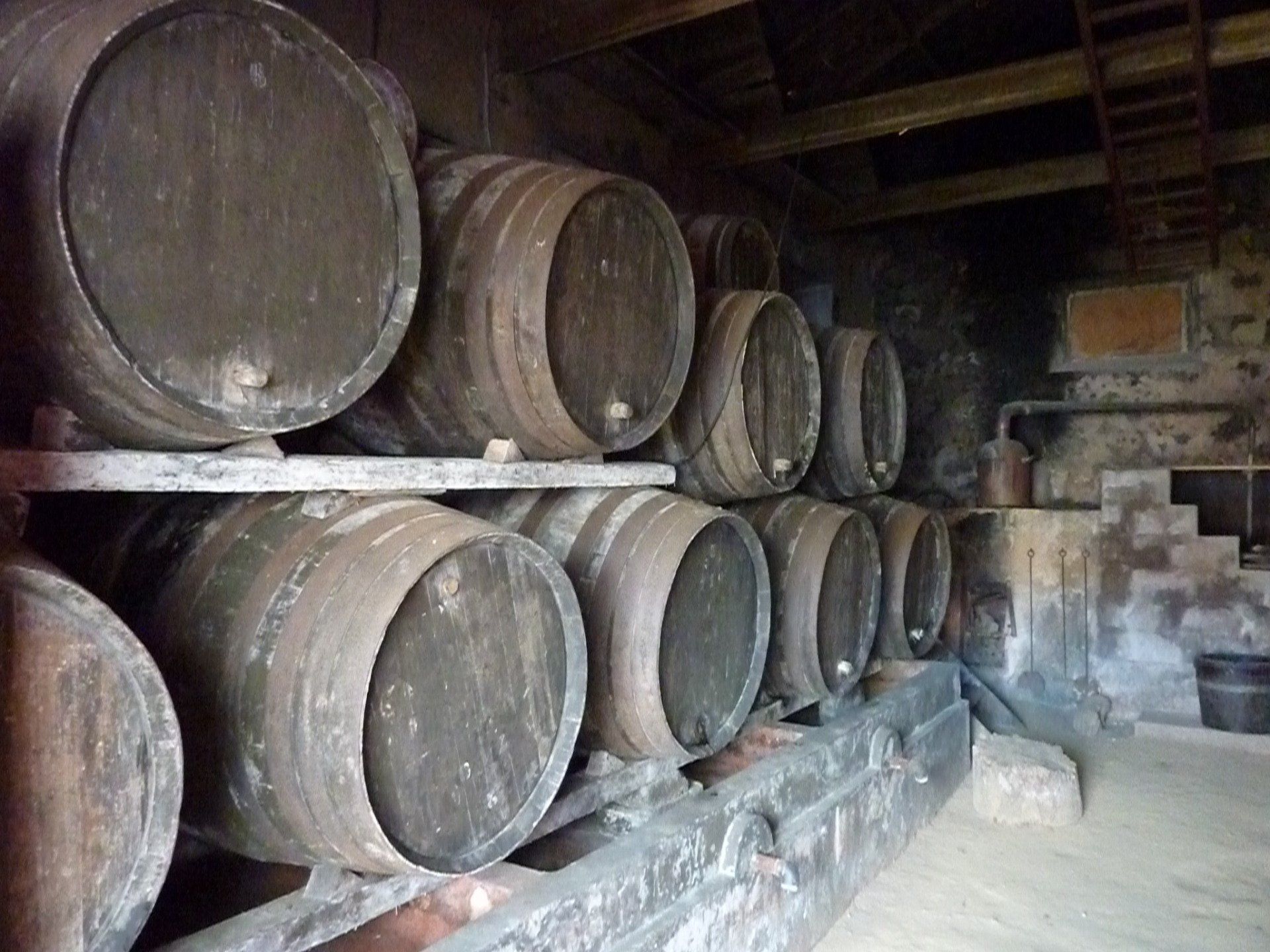 Houten vaten opgestapeld in een kelder, wat duidt op het rijpen of opslaan van wijn.