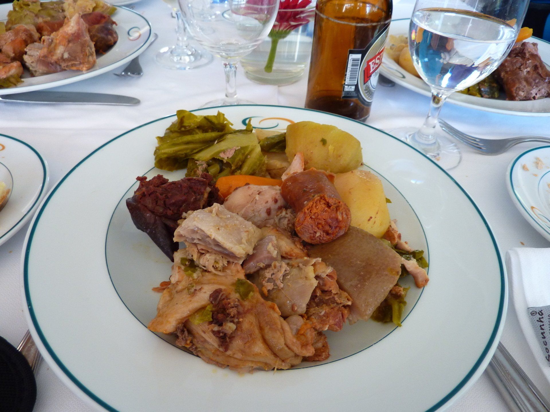 Bord met eten: diverse soorten vlees, worst, groenten en aardappelen.