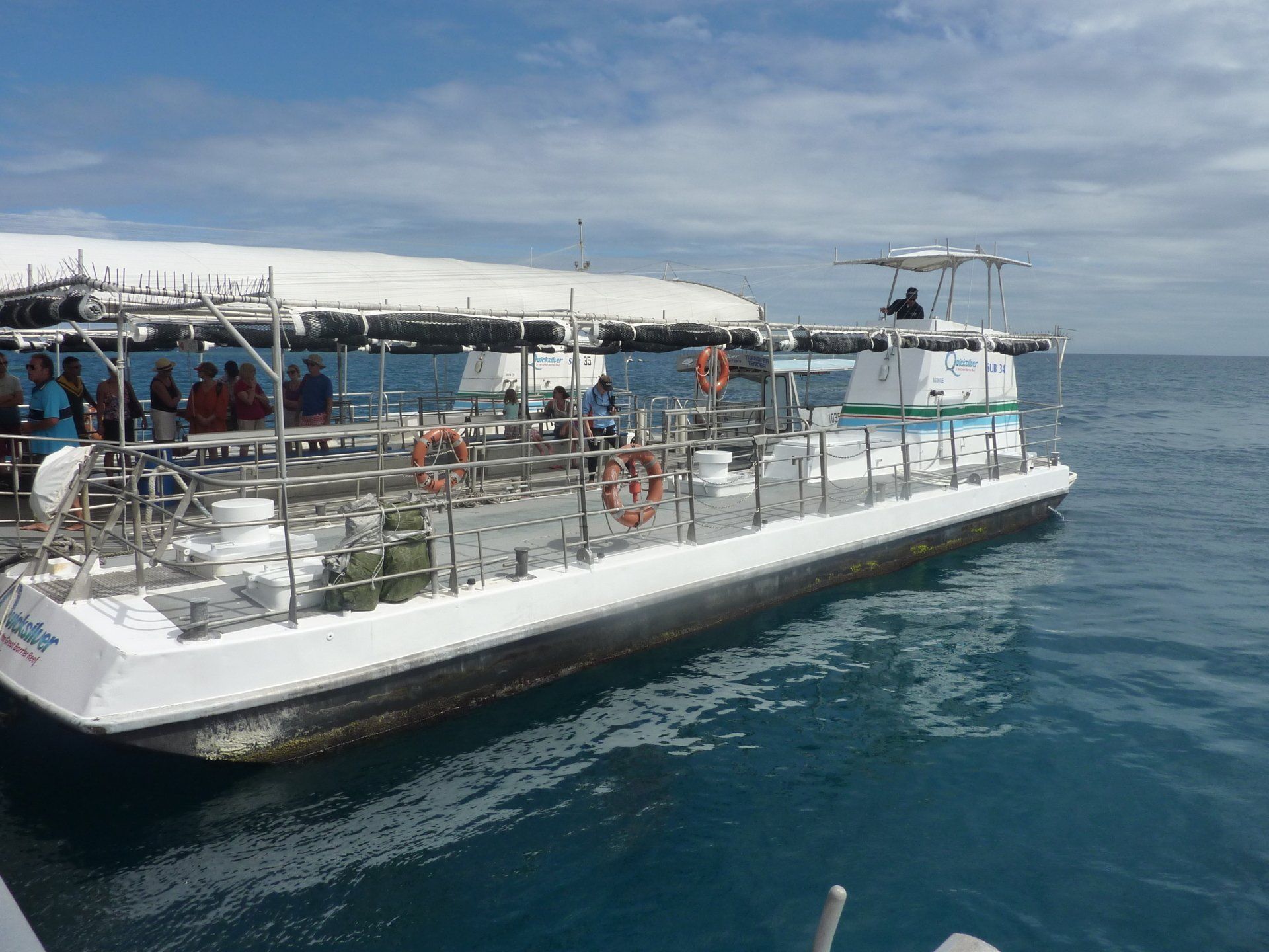 Witte boot met passagiers op het water; blauwe zee en lucht.