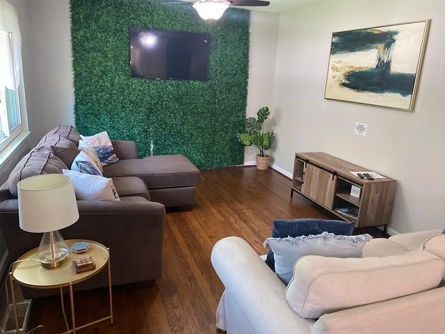 A living room with a couch , chairs , and a flat screen tv
