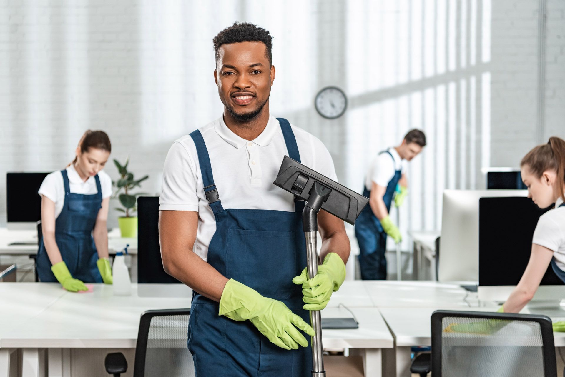 A man is holding a vacuum cleaner in an office.