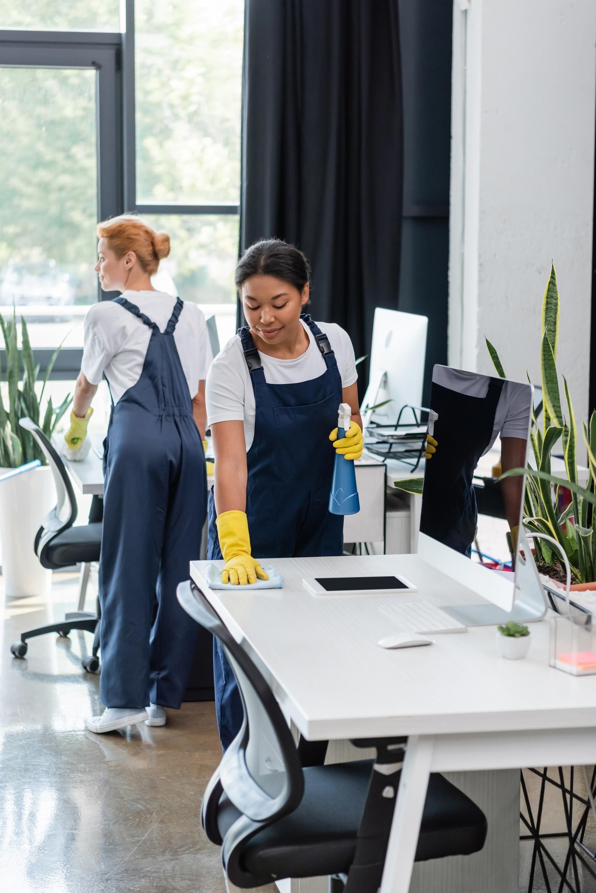 A woman is cleaning a desk in an office.