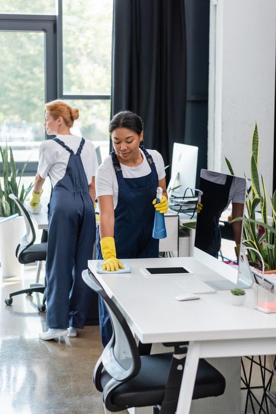 A woman is cleaning a desk in an office.