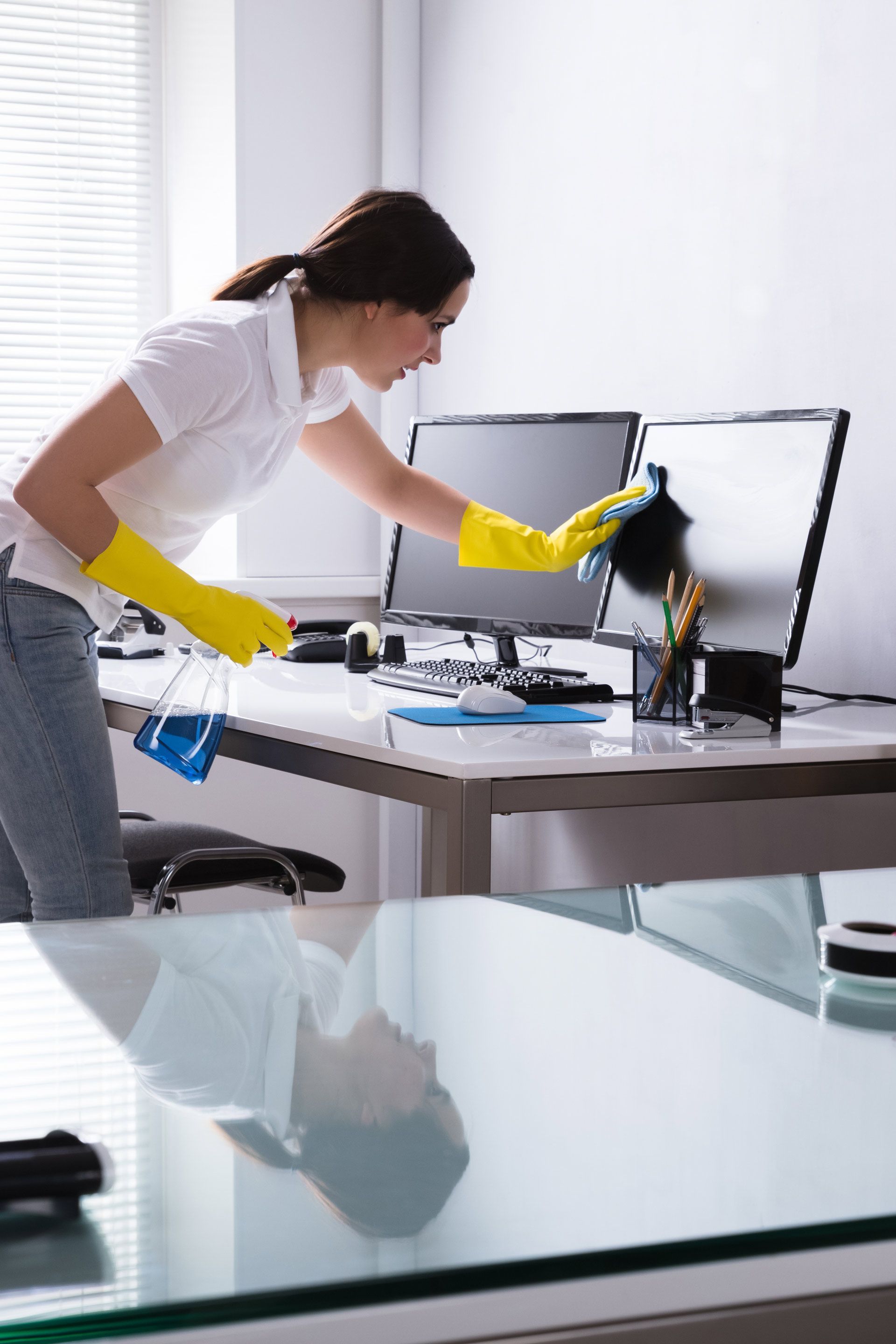 A woman is cleaning a computer screen in an office.