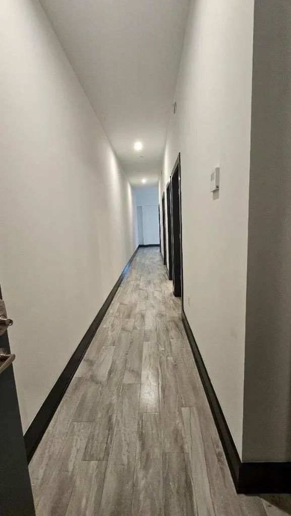A long hallway with a wooden floor and white walls.