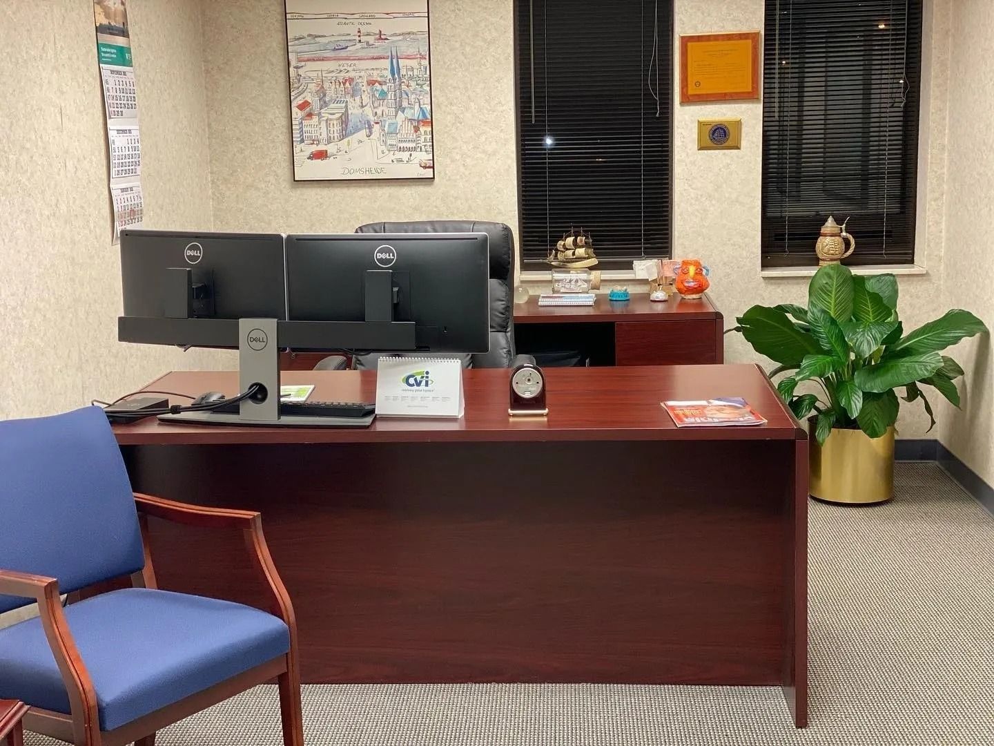A waiting room with a desk , chair and two computer monitors.