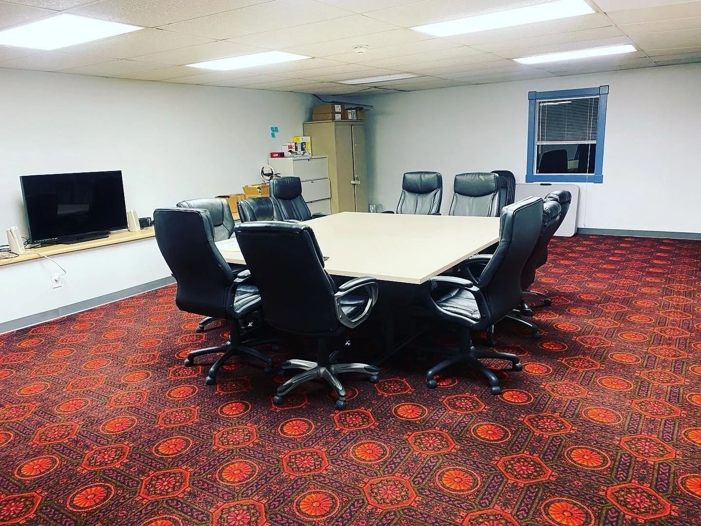 A conference room with a table and chairs and a television.