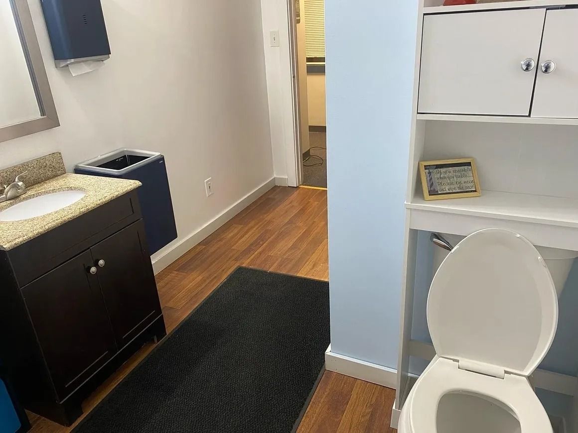 A bathroom with a toilet , sink and mirror