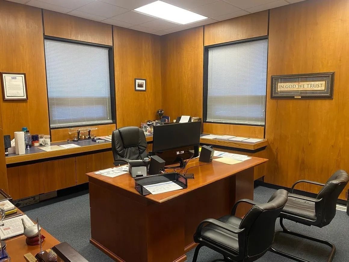 A wooden office with a desk , chairs and a computer.