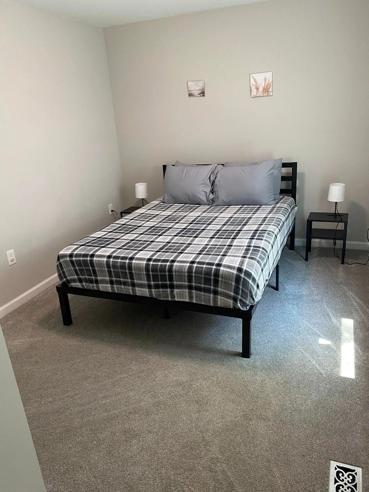 A bedroom with a king size bed and two lamps.