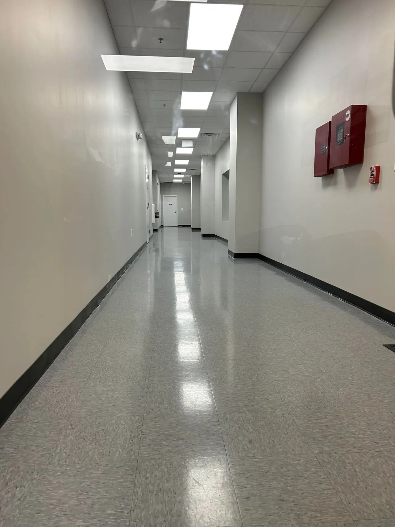 A long hallway with a fire extinguisher on the wall.