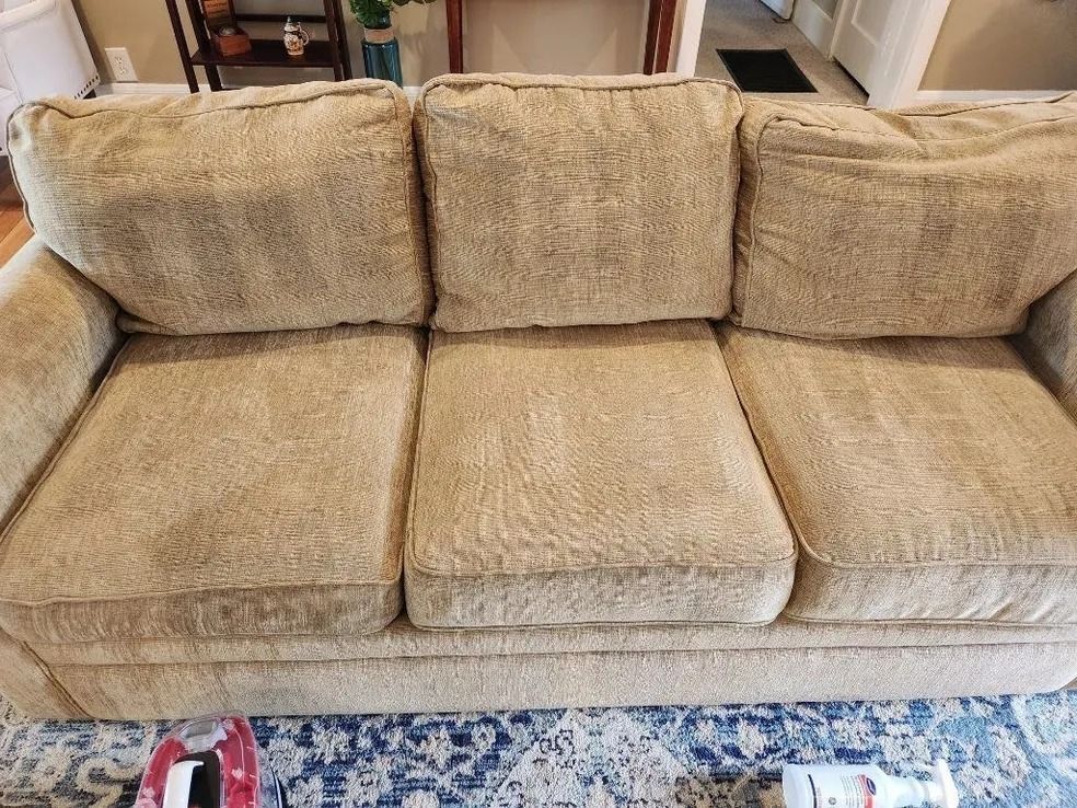 A beige couch is sitting on a rug in a living room.