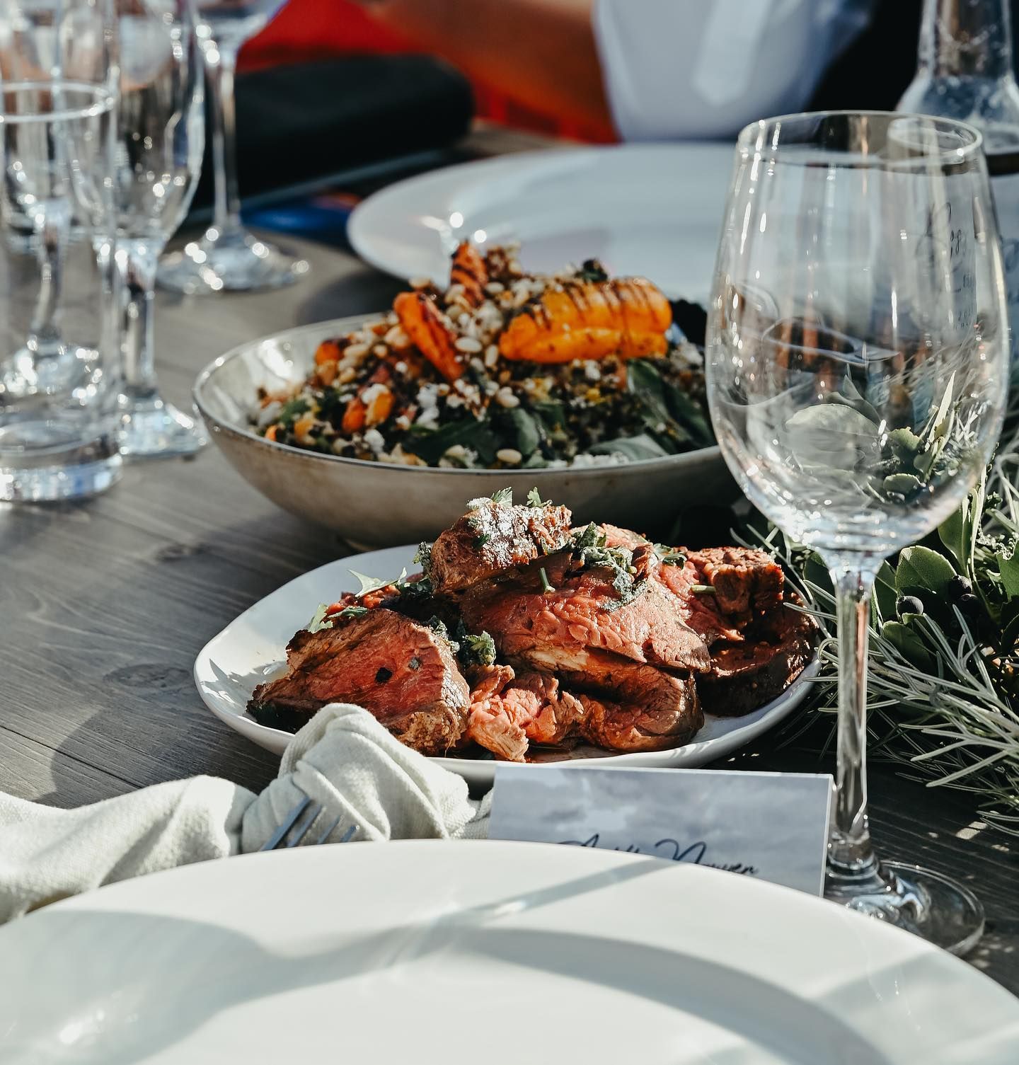 Table setting with dishes, wine glasses, and food.