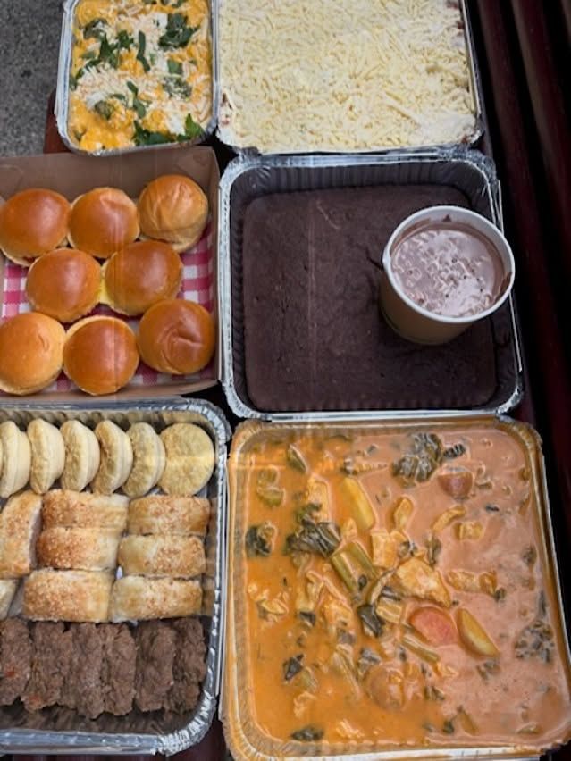 Various foil containers filled with food: rolls, dessert, casserole, soup.