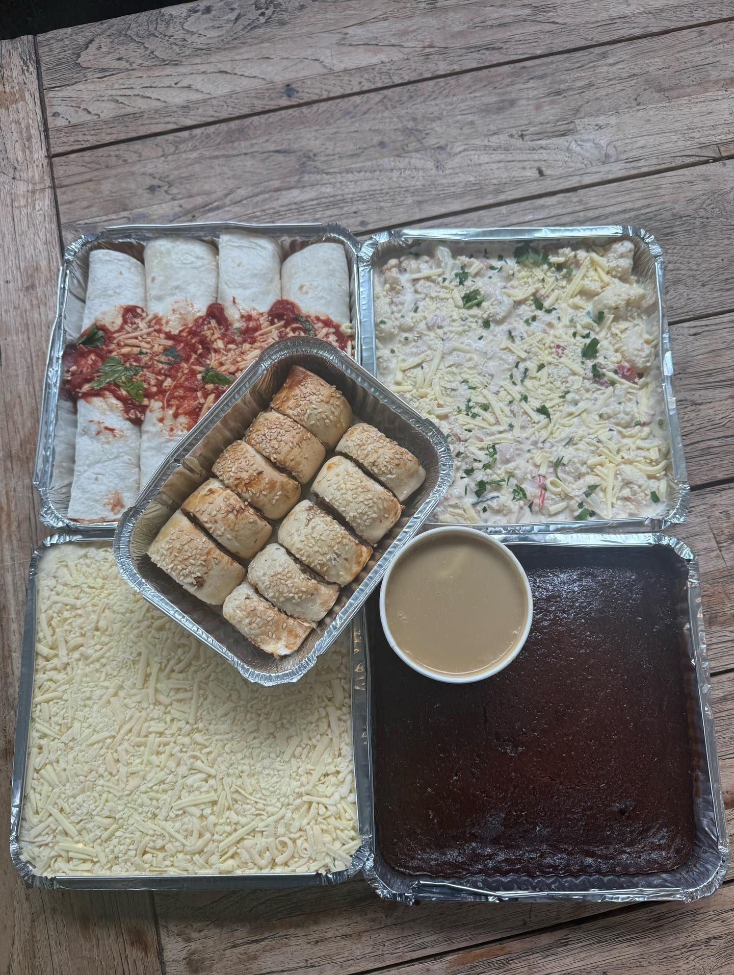 Food containers of various dishes: enchiladas, rolls, shredded cheese, casserole, dessert, and sauce.