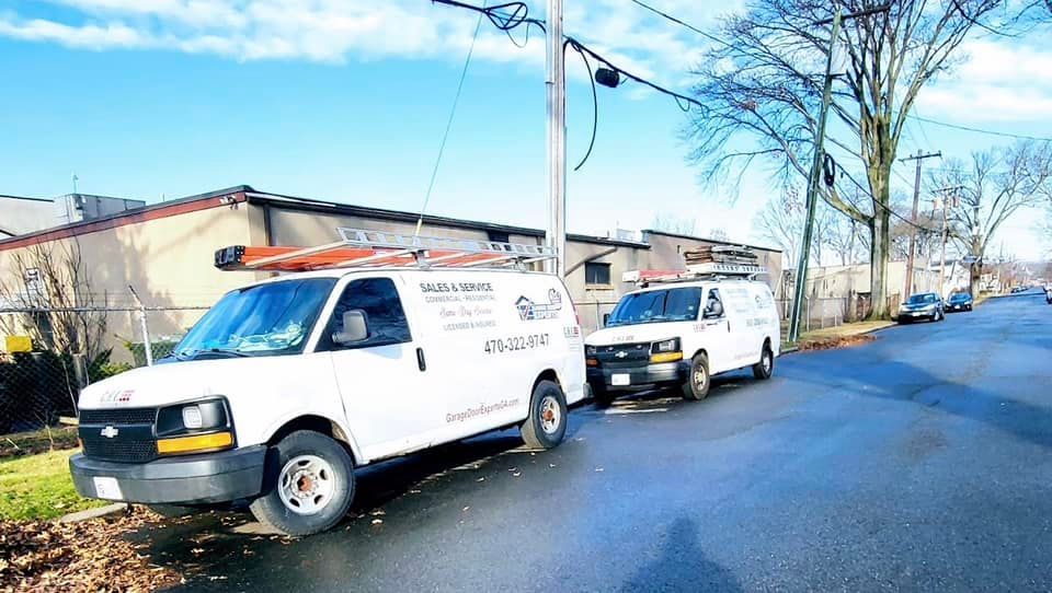 Two white vans are parked on the side of the road