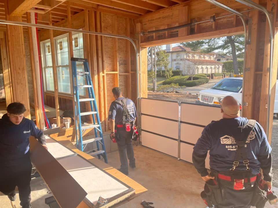 A group of men are working on a garage door.