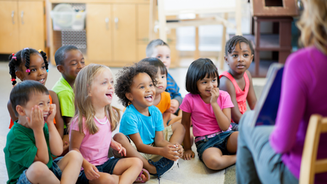 A group of children are sitting on the floor listening to a story.