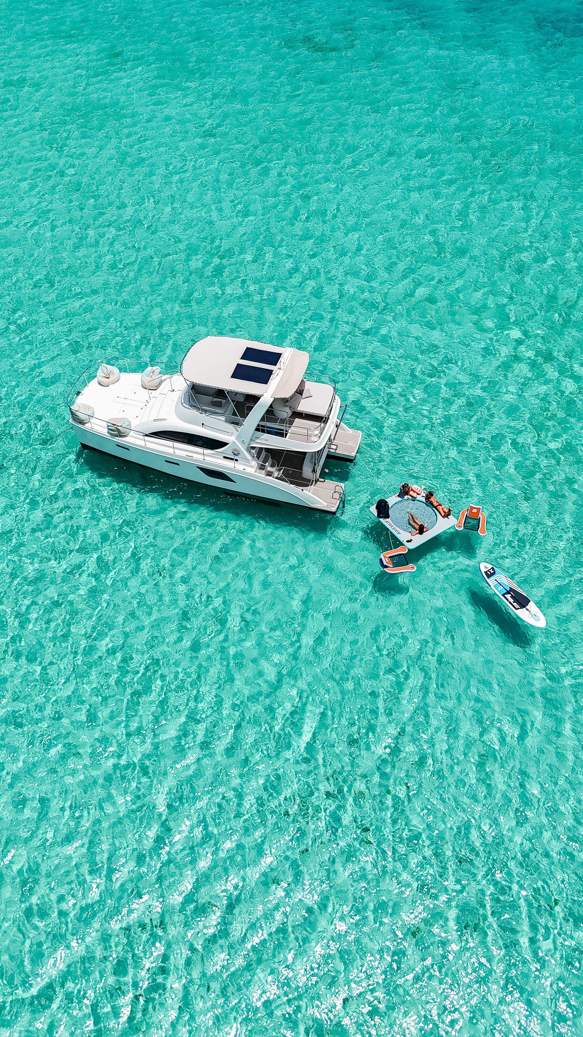 White catamaran and floating platform in clear turquoise water.