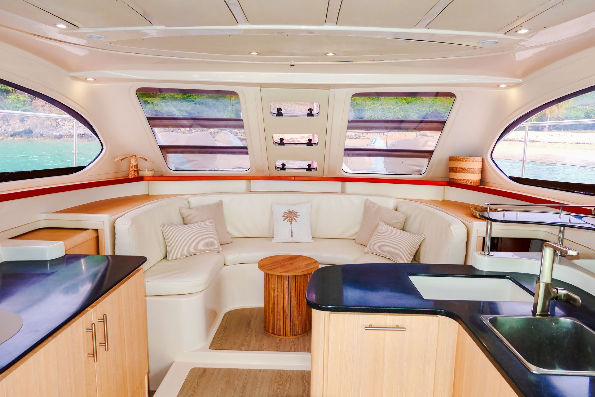 Interior of a yacht with white seating, wooden accents, and large windows overlooking the water.