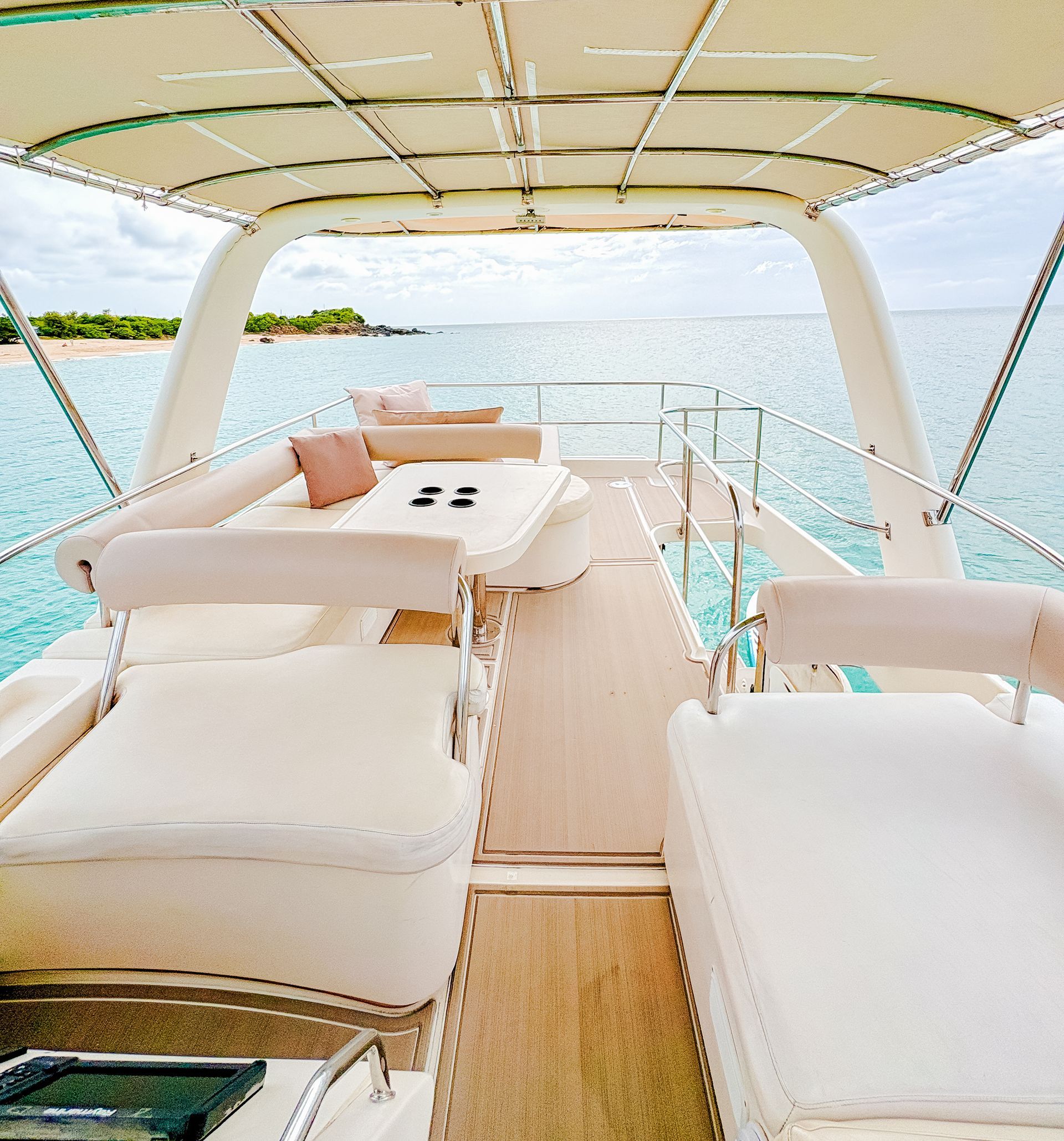 A boat deck with seating, table, and ocean view on a sunny day.