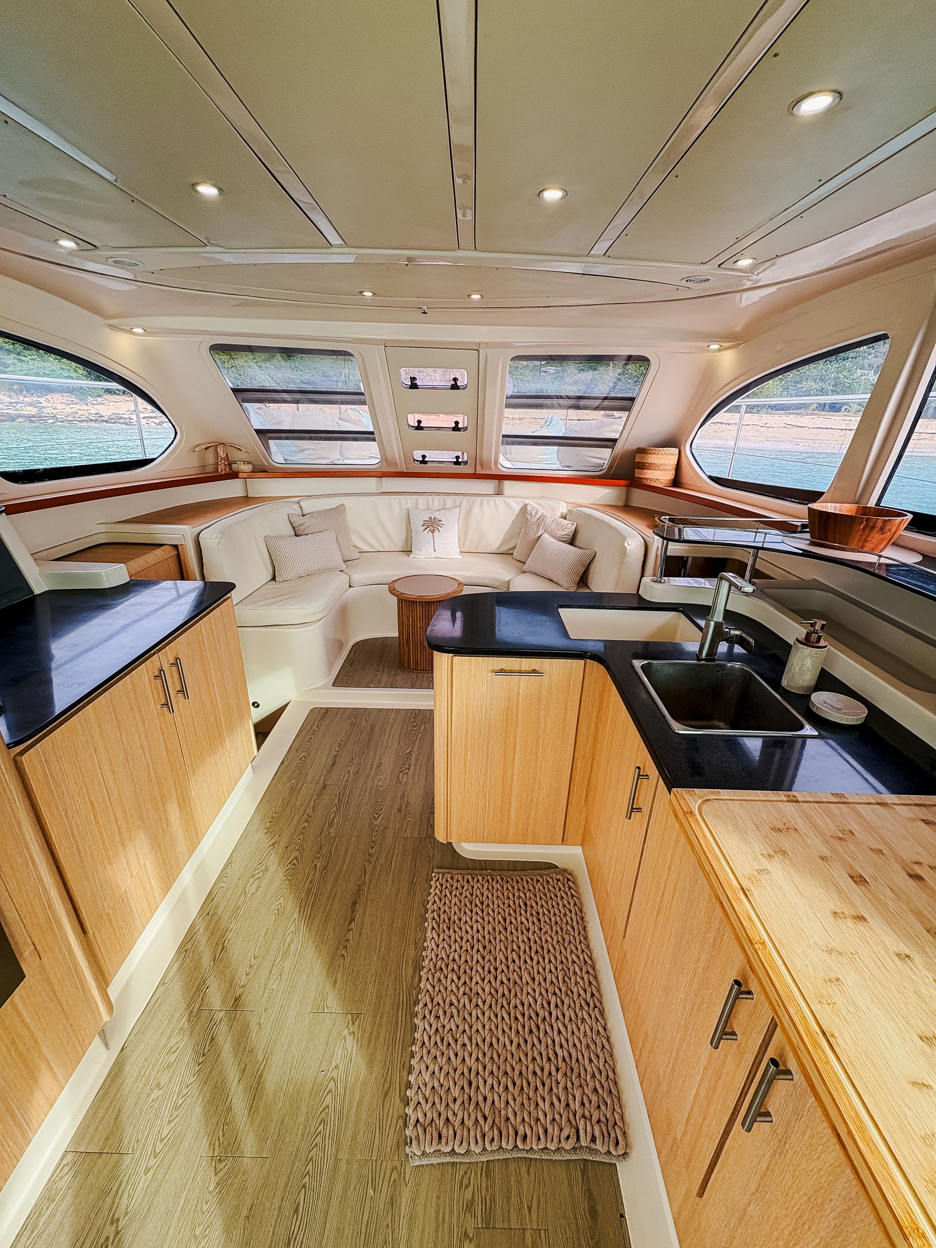 Interior view of a yacht cabin with beige cabinets, white seating, and large windows.