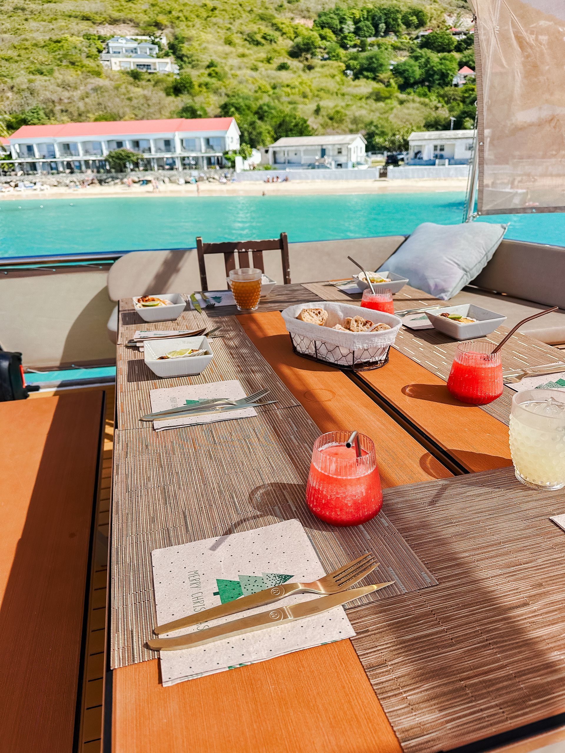Breakfast table set on a boat with ocean view, fruit drinks and food.