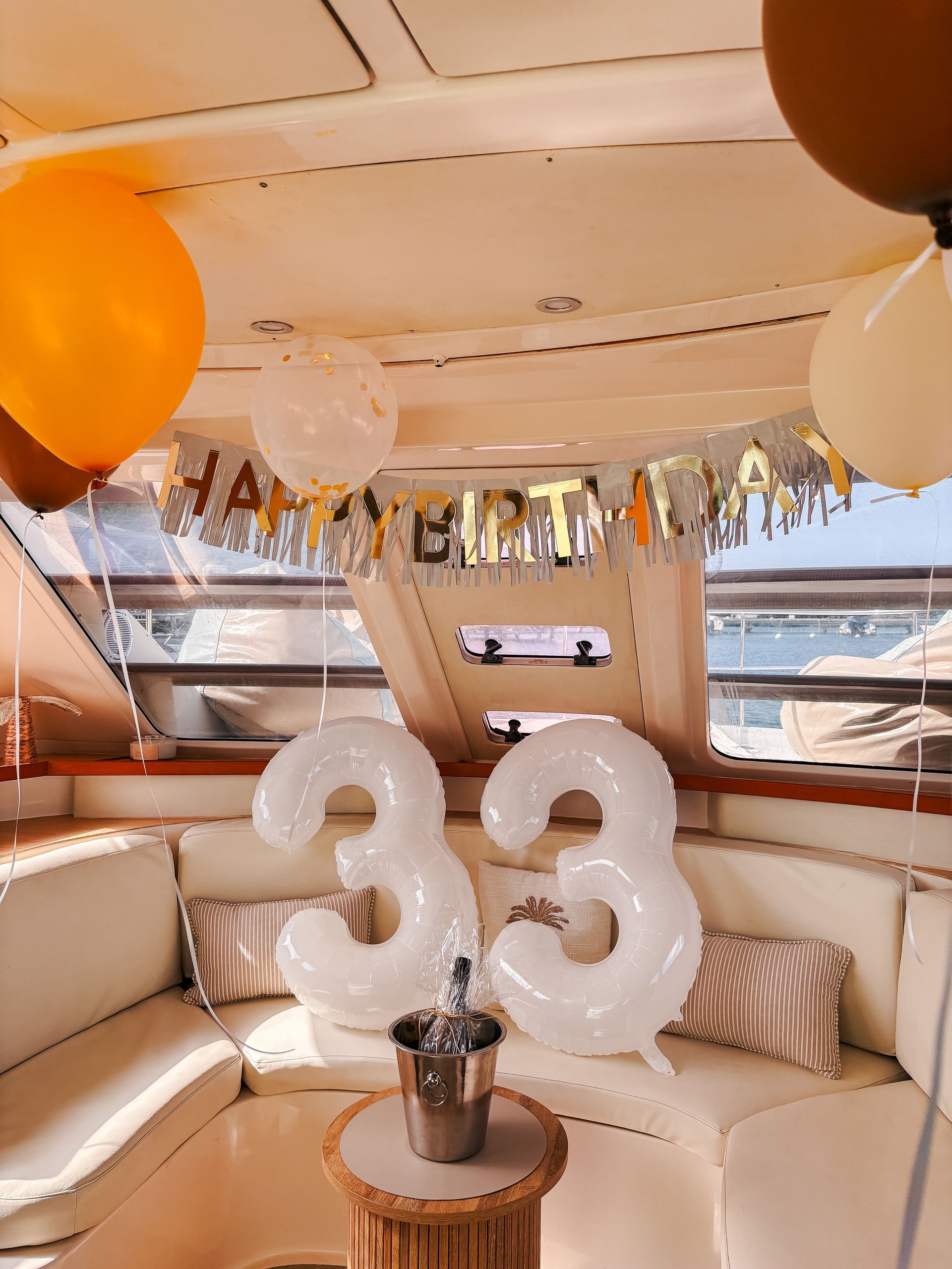 A yacht interior decorated for a 33rd birthday with balloons and a banner.