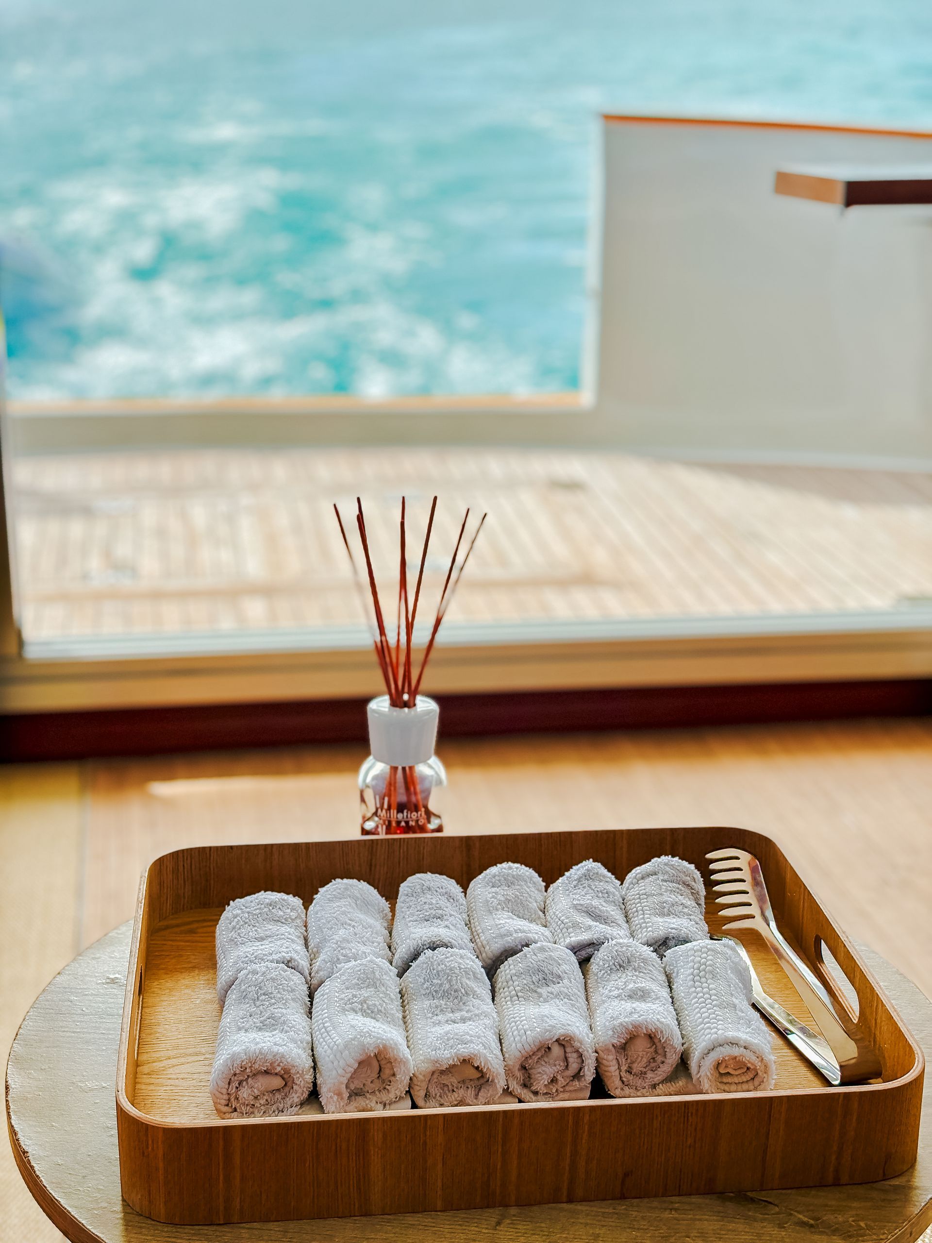 Tray of powdered-sugar-covered Turkish delight rolls, reed diffuser, overlooking ocean view from a room.