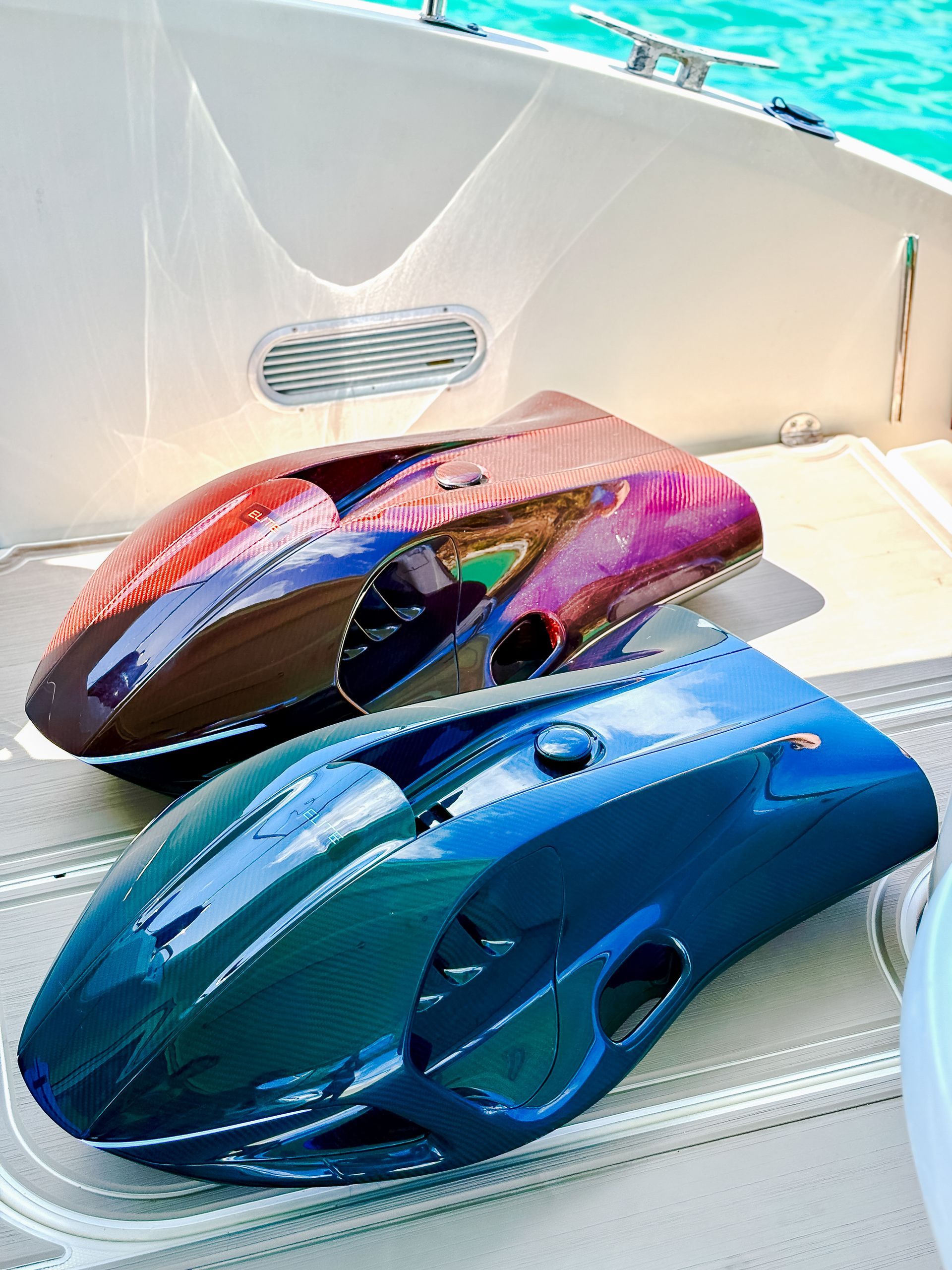 Two metallic-painted boat hatches, brown and blue, sitting on a boat deck.