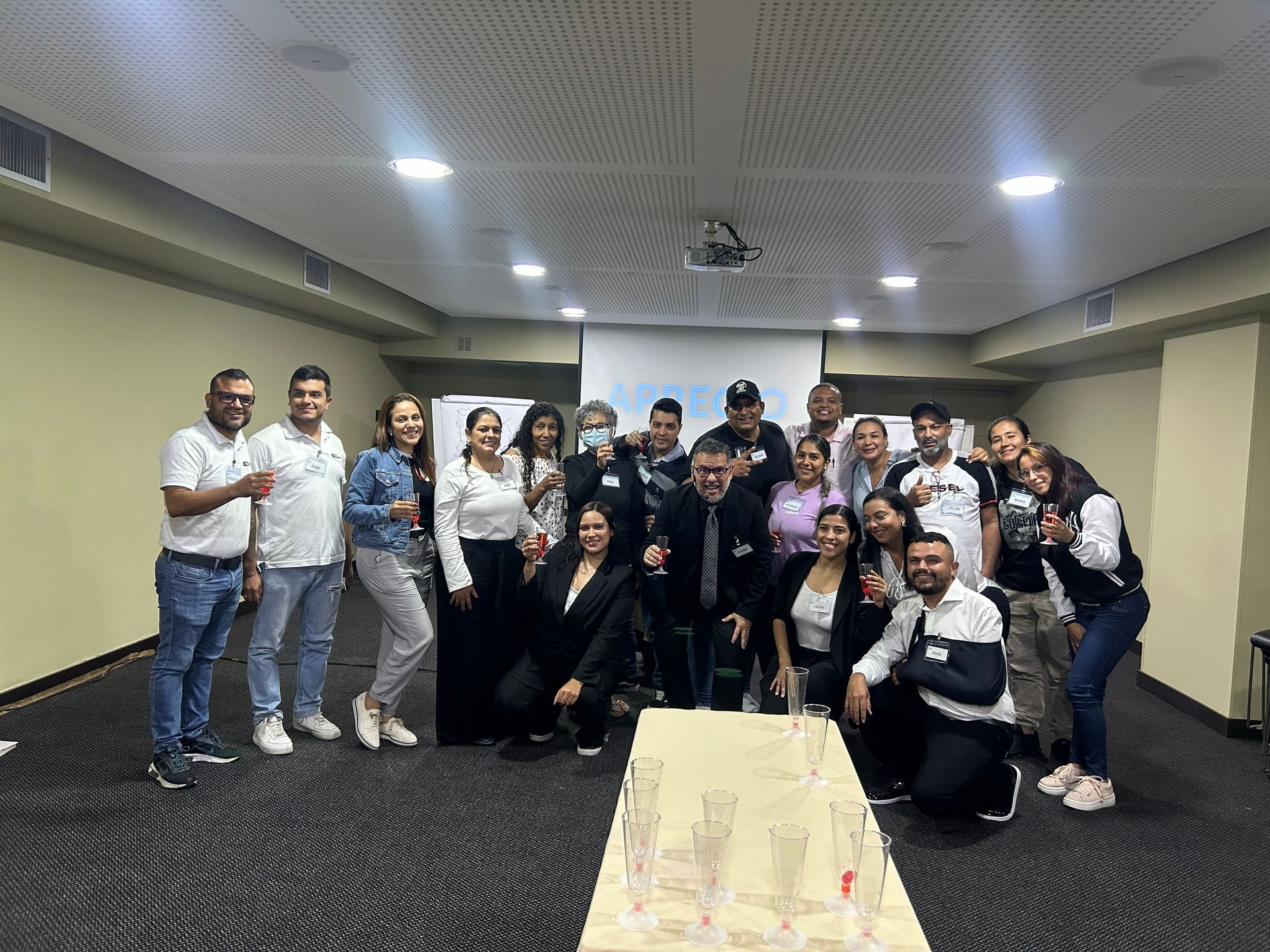 Un grupo de personas de pie en una sala de conferencias, posando para una foto detrás de una mesa 