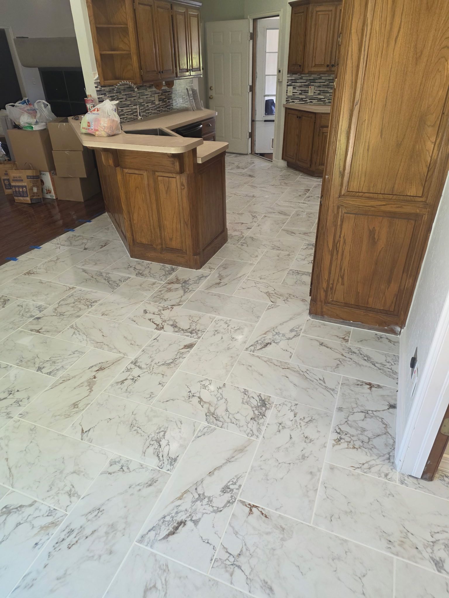Kitchen with white marble floor tiles, wooden cabinets, and an island in the center