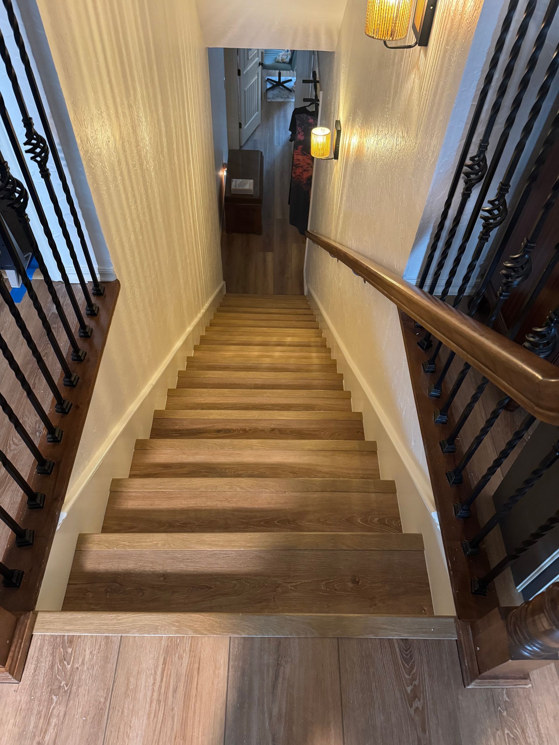 Narrow indoor staircase with carpeted steps, black railings, and warm wall sconces.