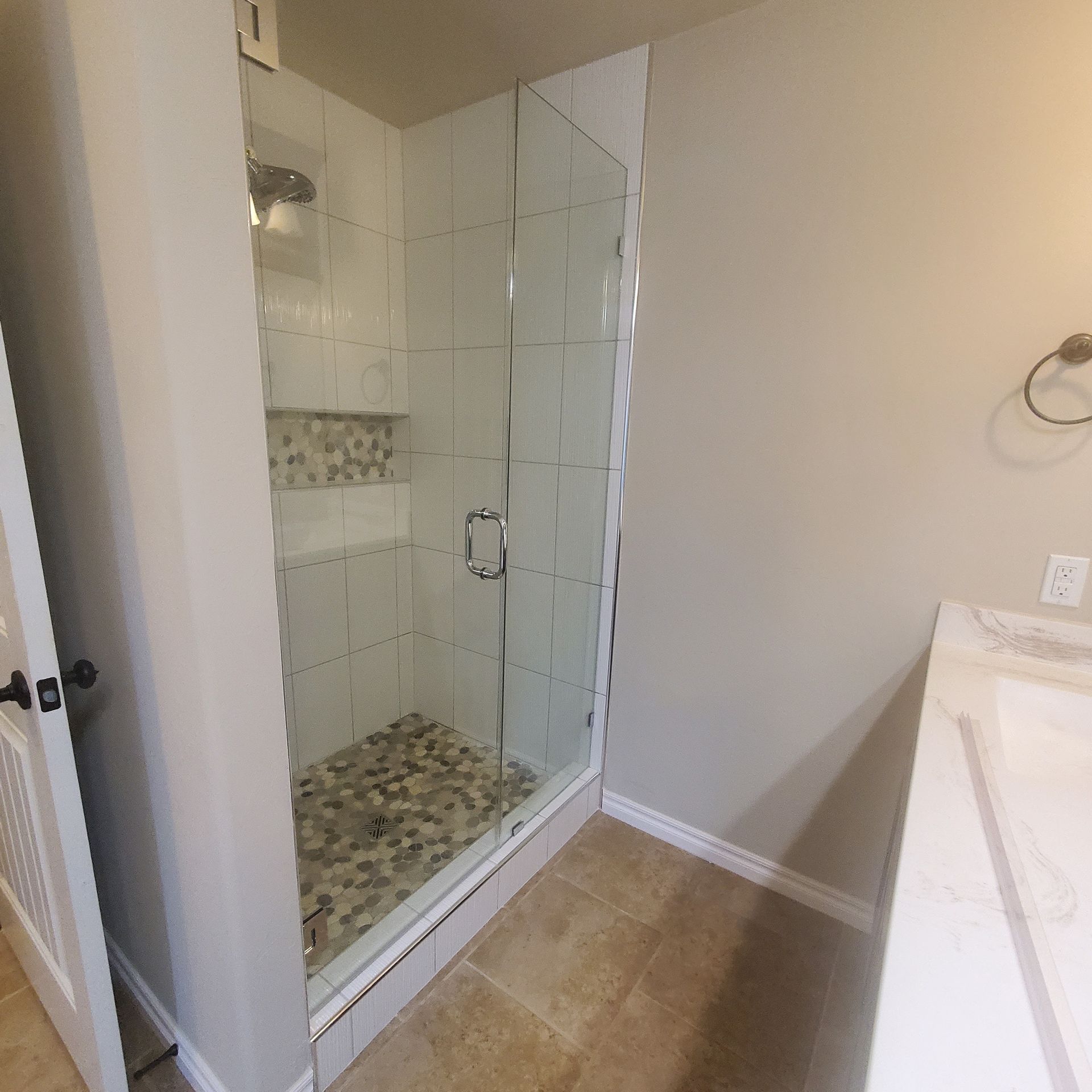 Bathroom with glass walk-in shower, beige tile floor, and white vanity sink.