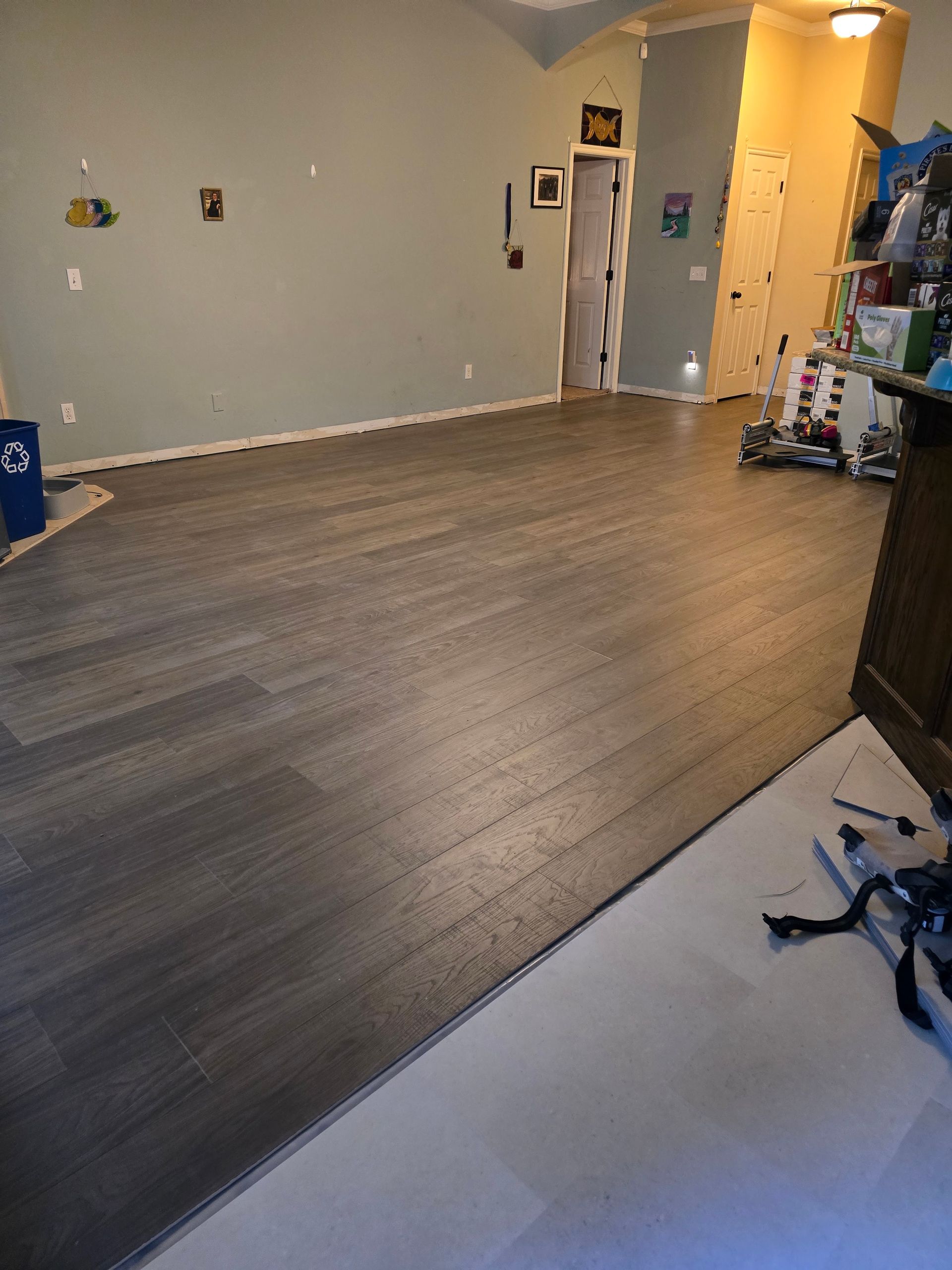 Empty room with gray walls, wood-look flooring, and an open doorway in the back.