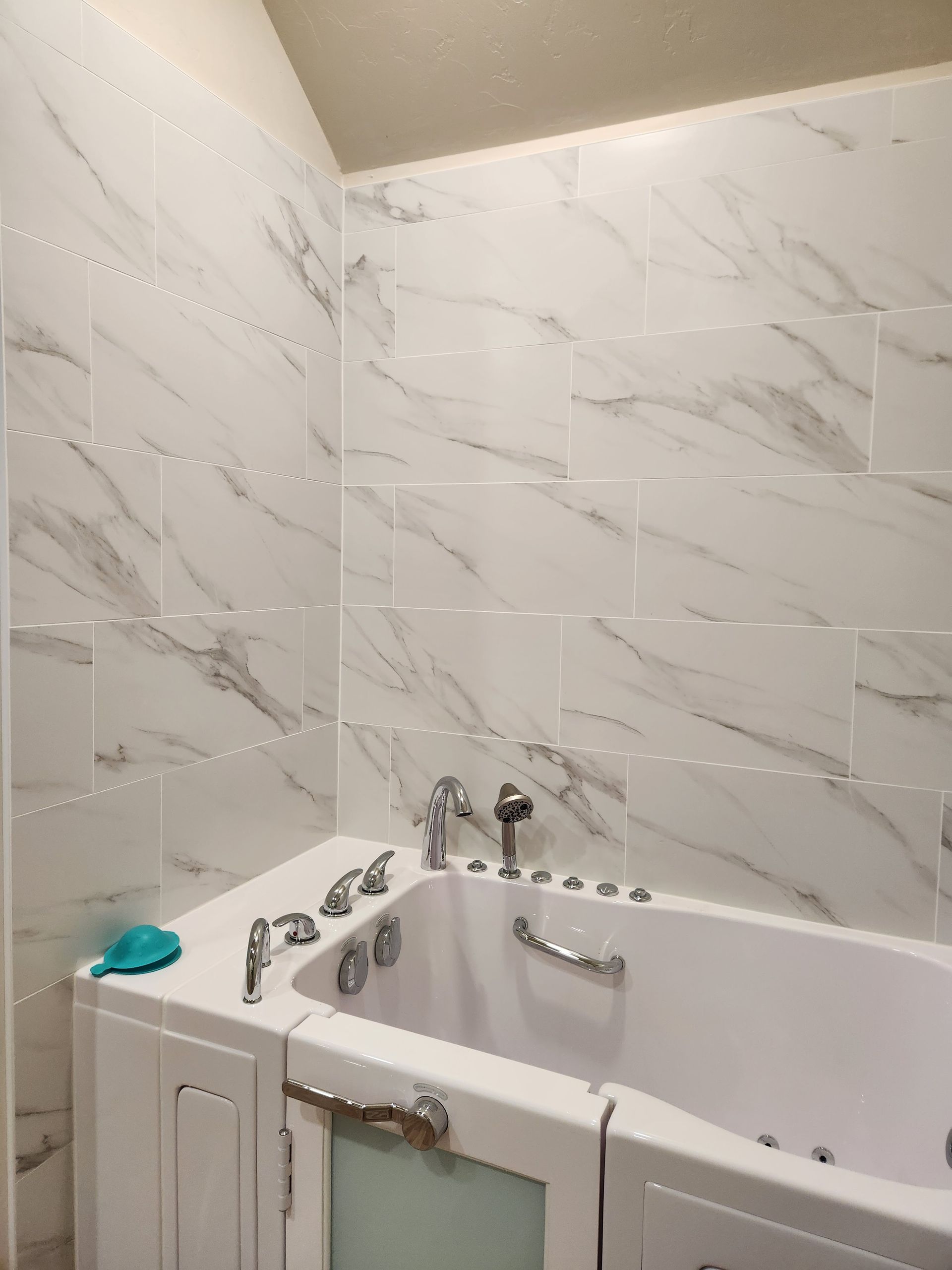 White marble-tiled bathroom with a white corner bathtub and chrome fixtures