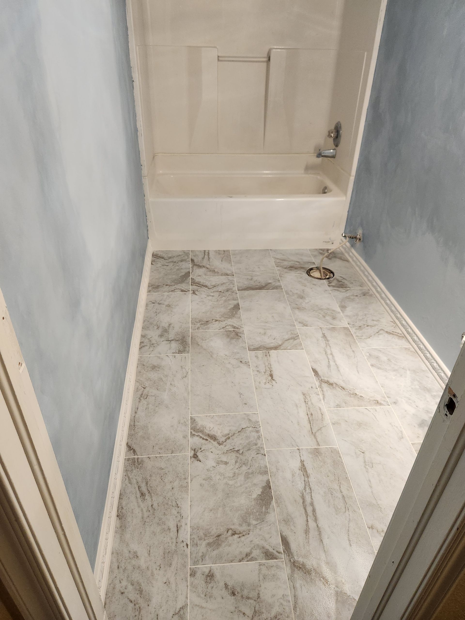 Small bathroom with a tub-shower and a floor covered in dust and debris, suggesting renovation.
