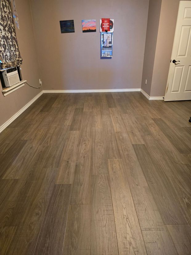 Empty room with wood floors, beige walls, and a few small wall decorations.