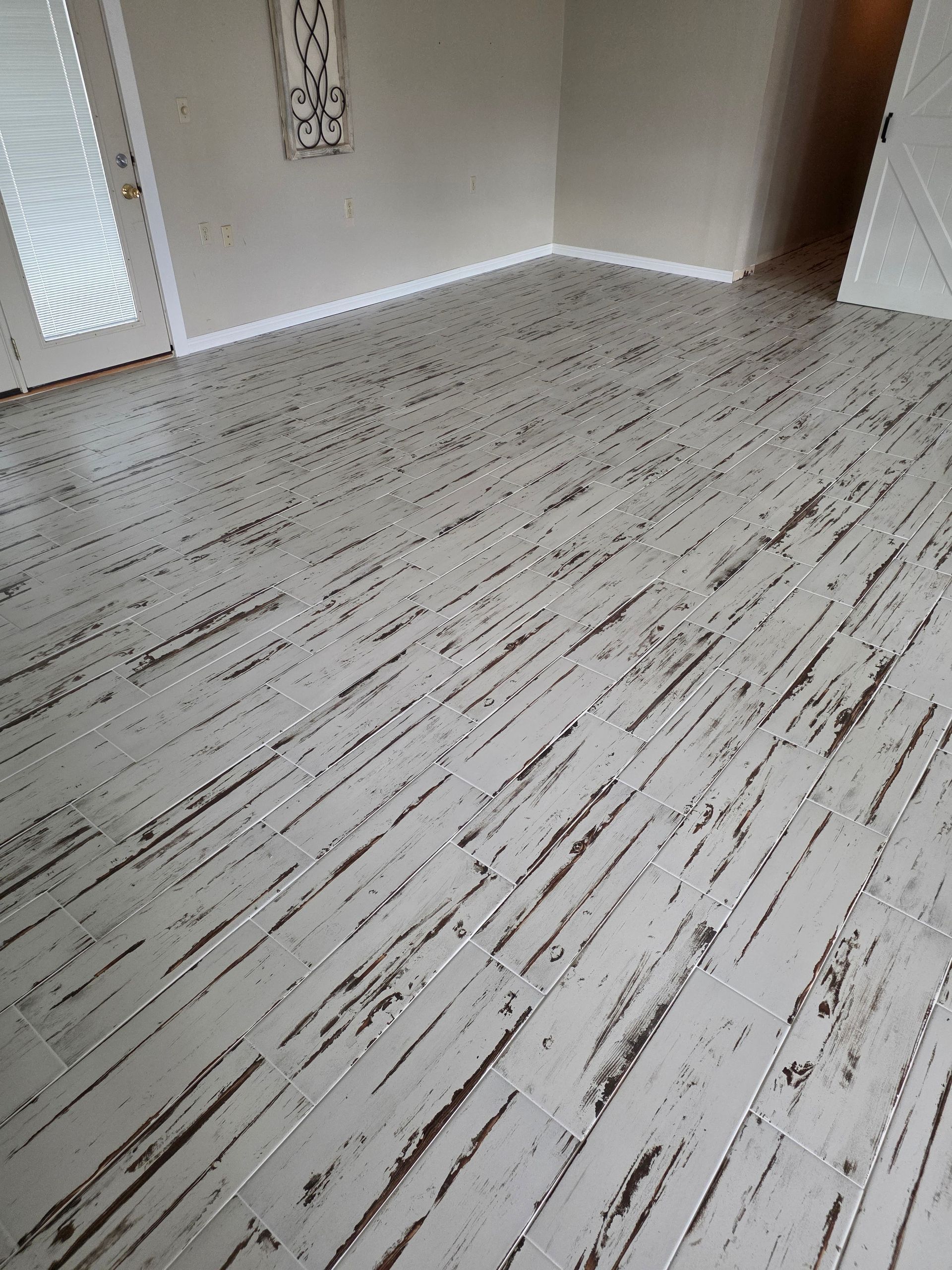 Empty room with light wood-look flooring and white walls near a doorway.