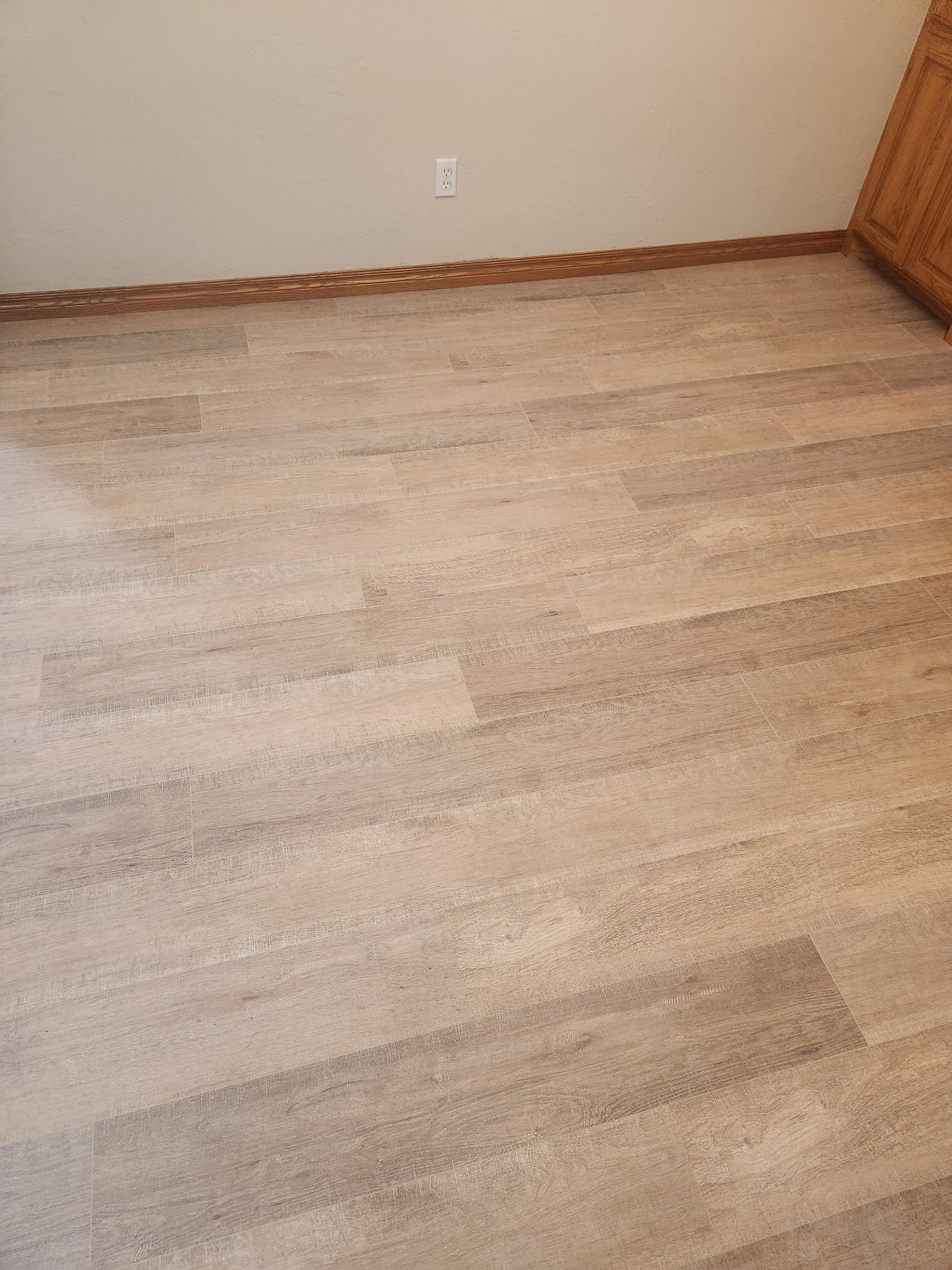 Empty room with light wood flooring, white walls, and brown trim.