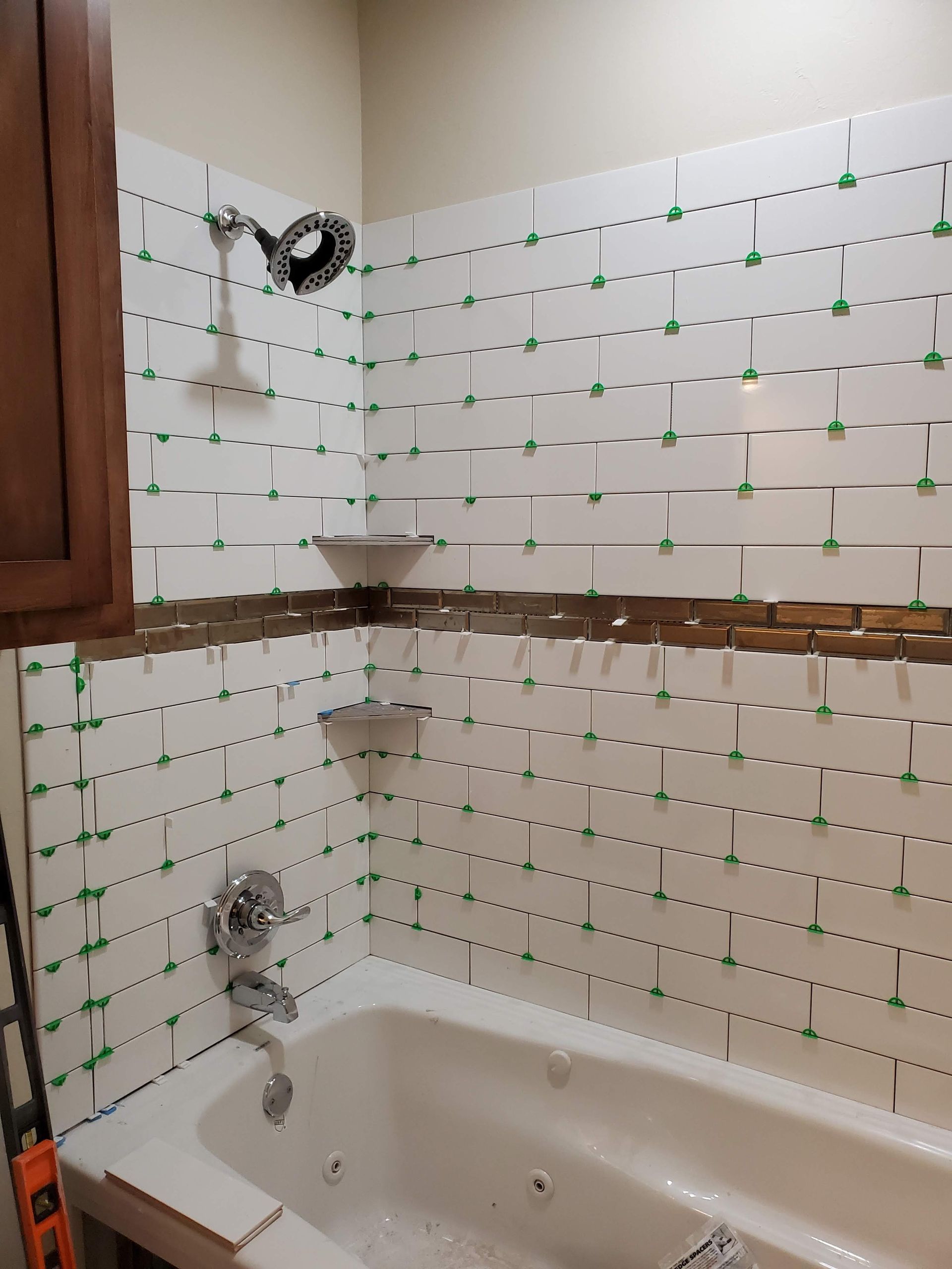 Partially tiled bathroom with a white bathtub and shower fixtures under renovation