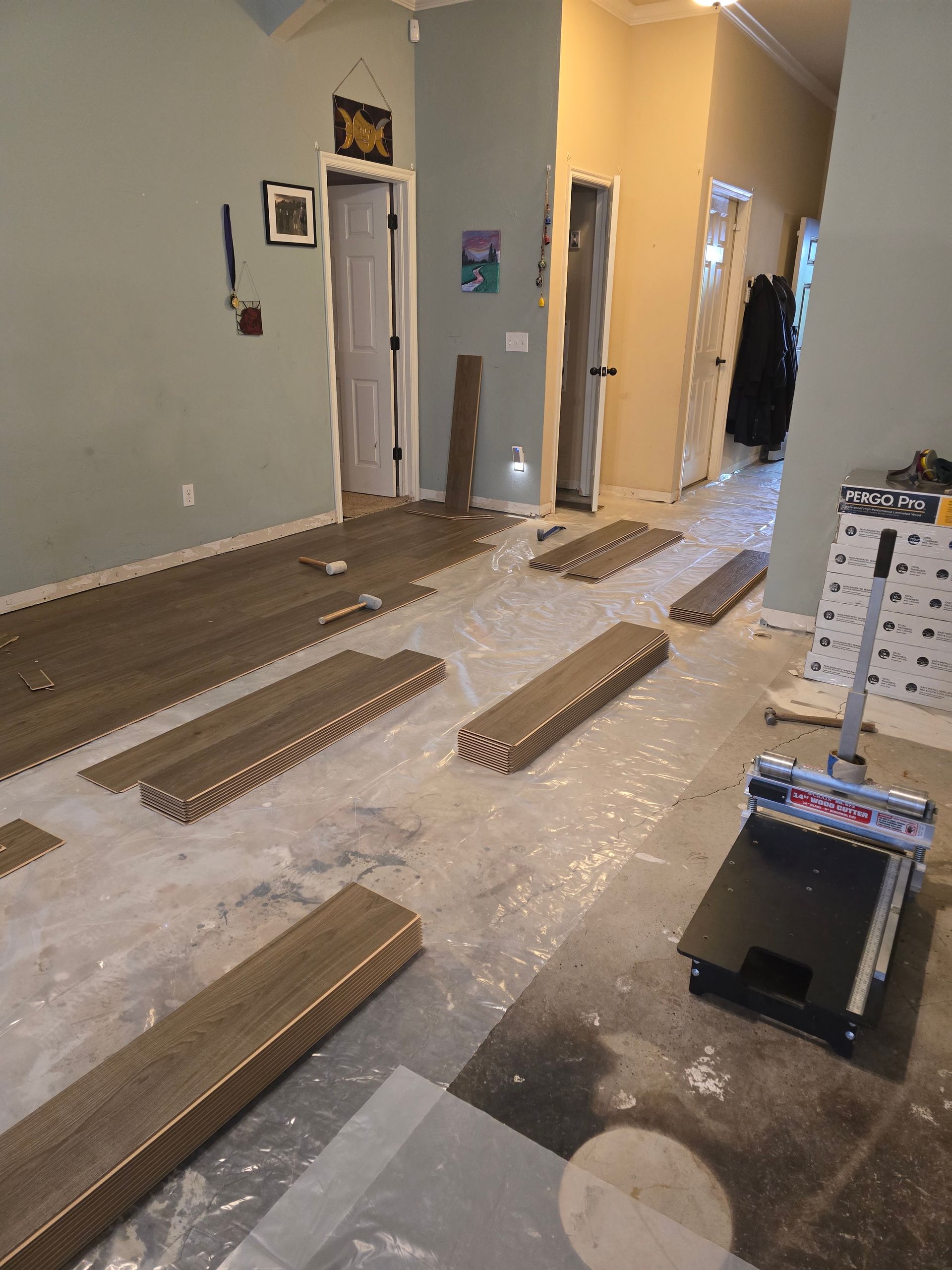 Living room with floorboards laid out over protective sheeting during renovation