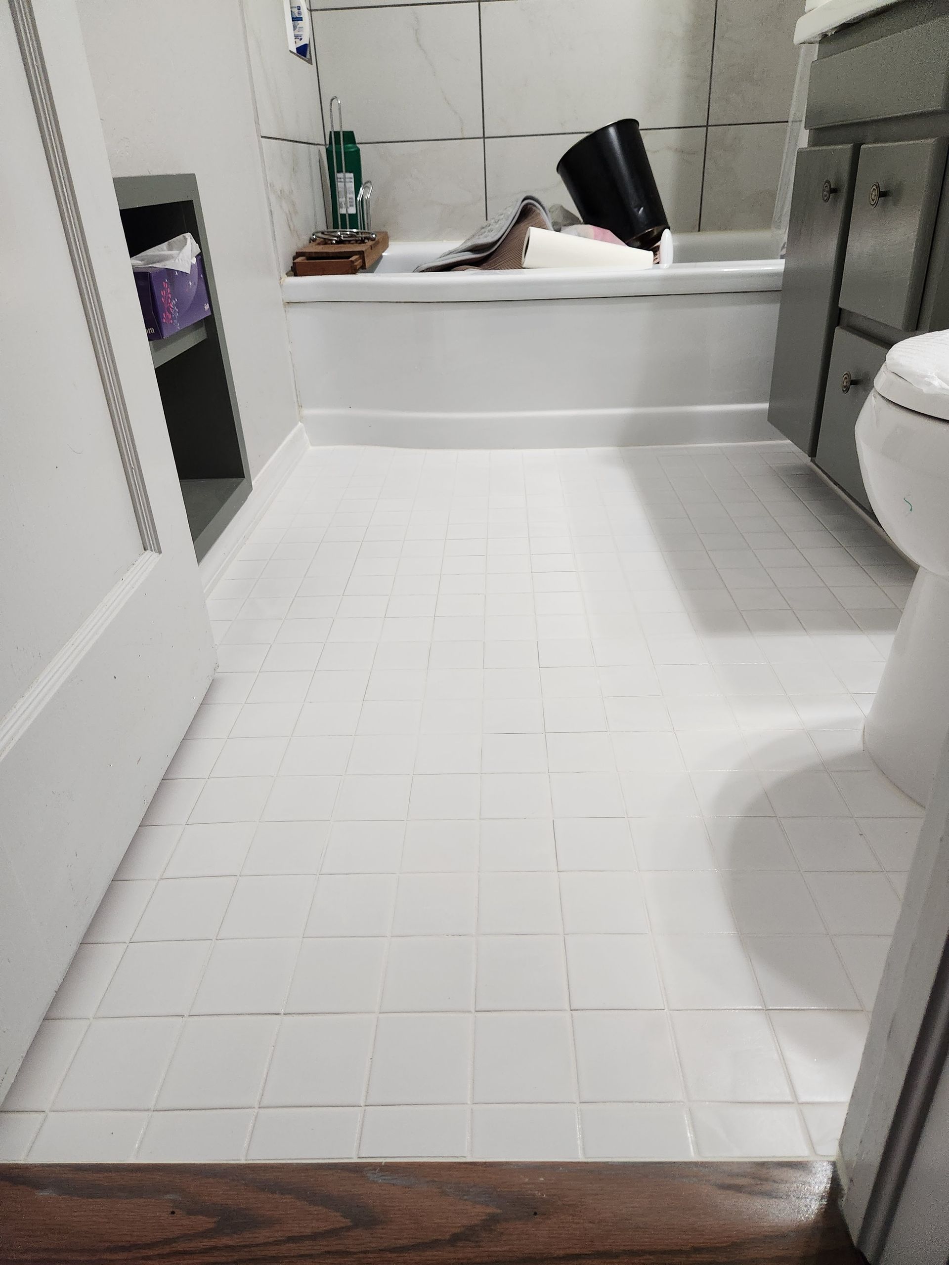 White tiled bathroom with a walk-in shower, bathtub, and toilet visible.