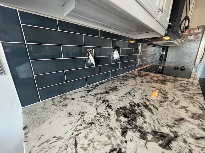 Modern kitchen with dark subway tile backsplash and white-and-black marble countertop