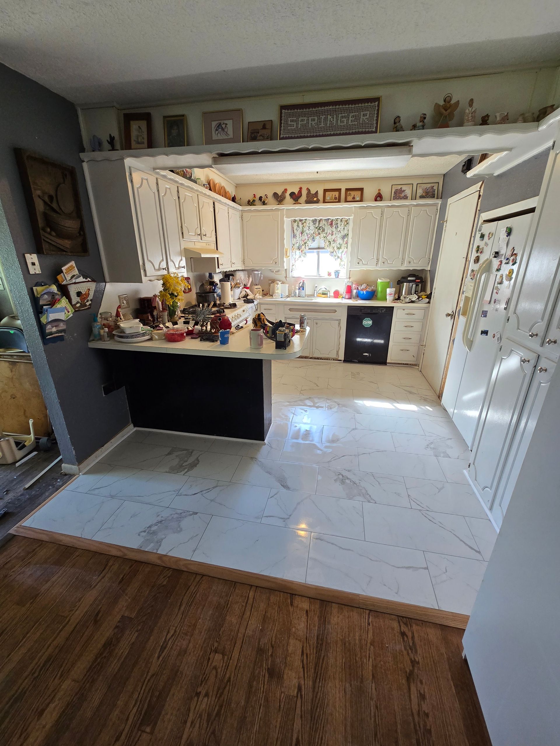 Bright kitchen with white cabinets, an island, tiled floor, and a window above the sink.
