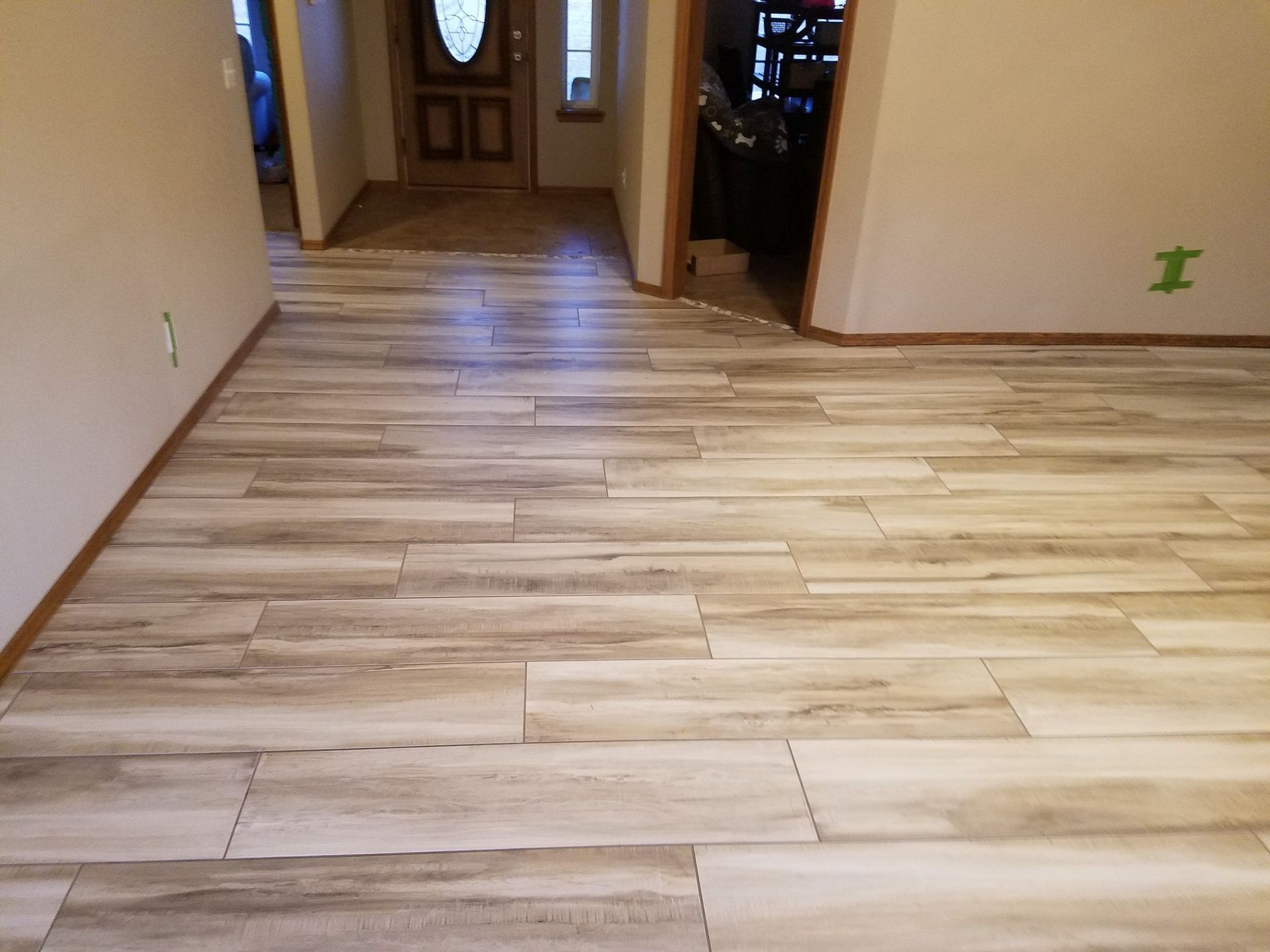 Empty hallway with light wood flooring and a front door at the far end