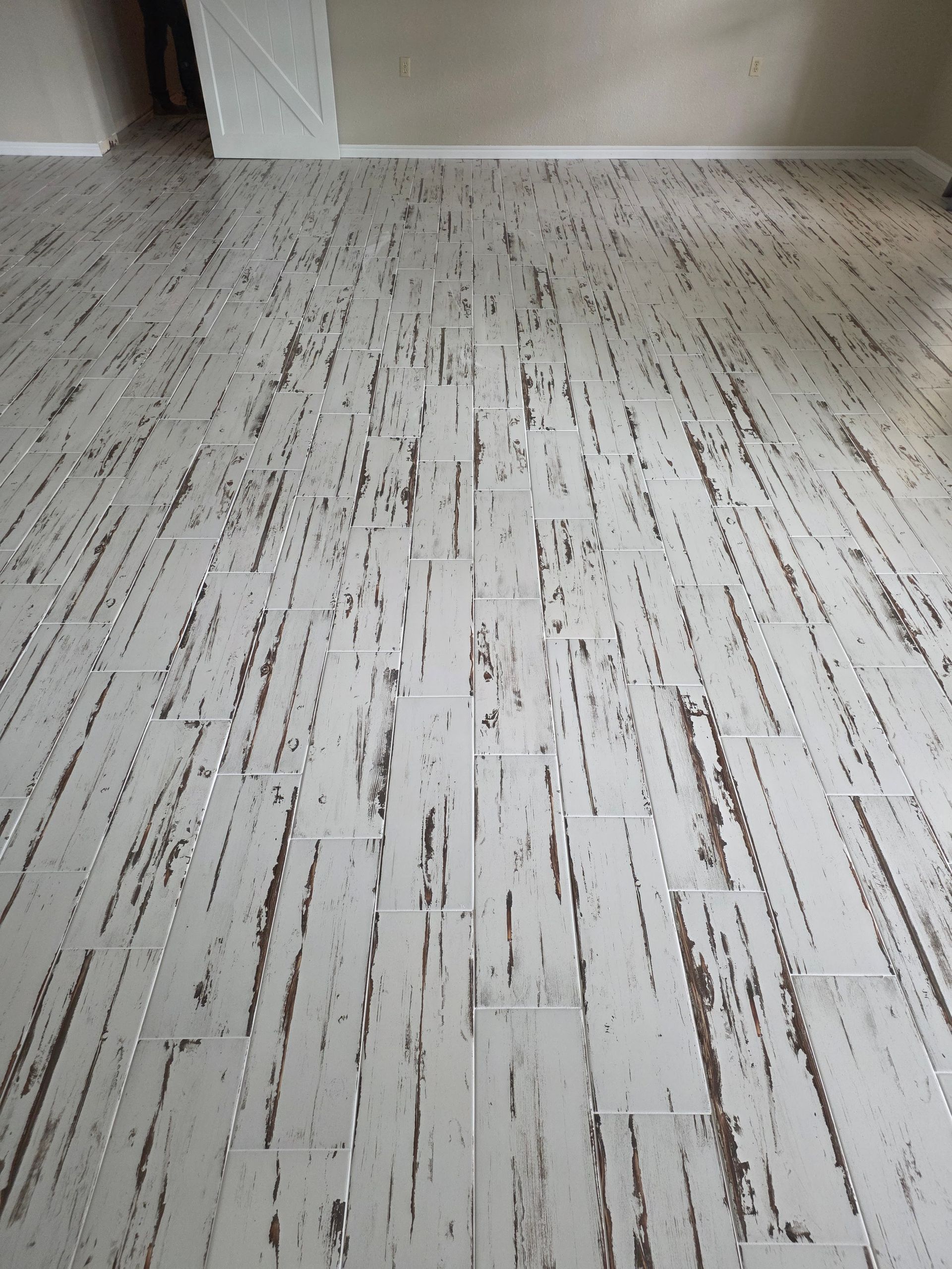 Light wood-patterned tile floor in an empty room, viewed from a low angle.