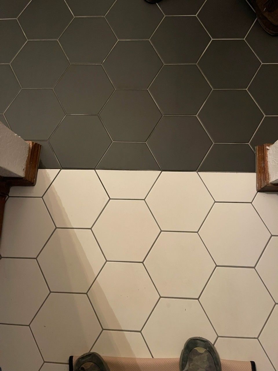 Hexagonal tile floor with dark gray tiles at top and white tiles below, viewed from above.