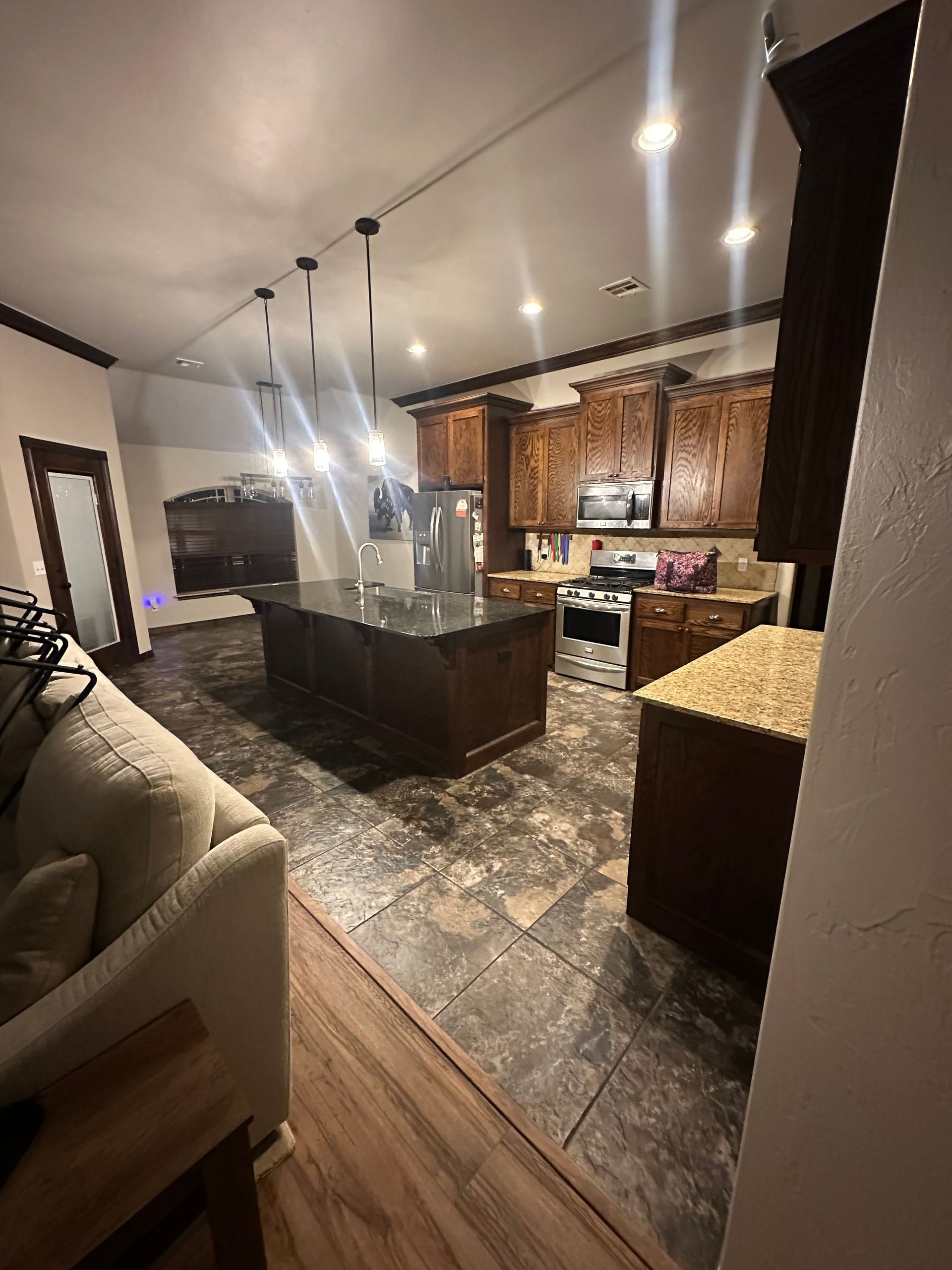 Modern kitchen and living room with dark cabinets, granite island, and patterned tile floor