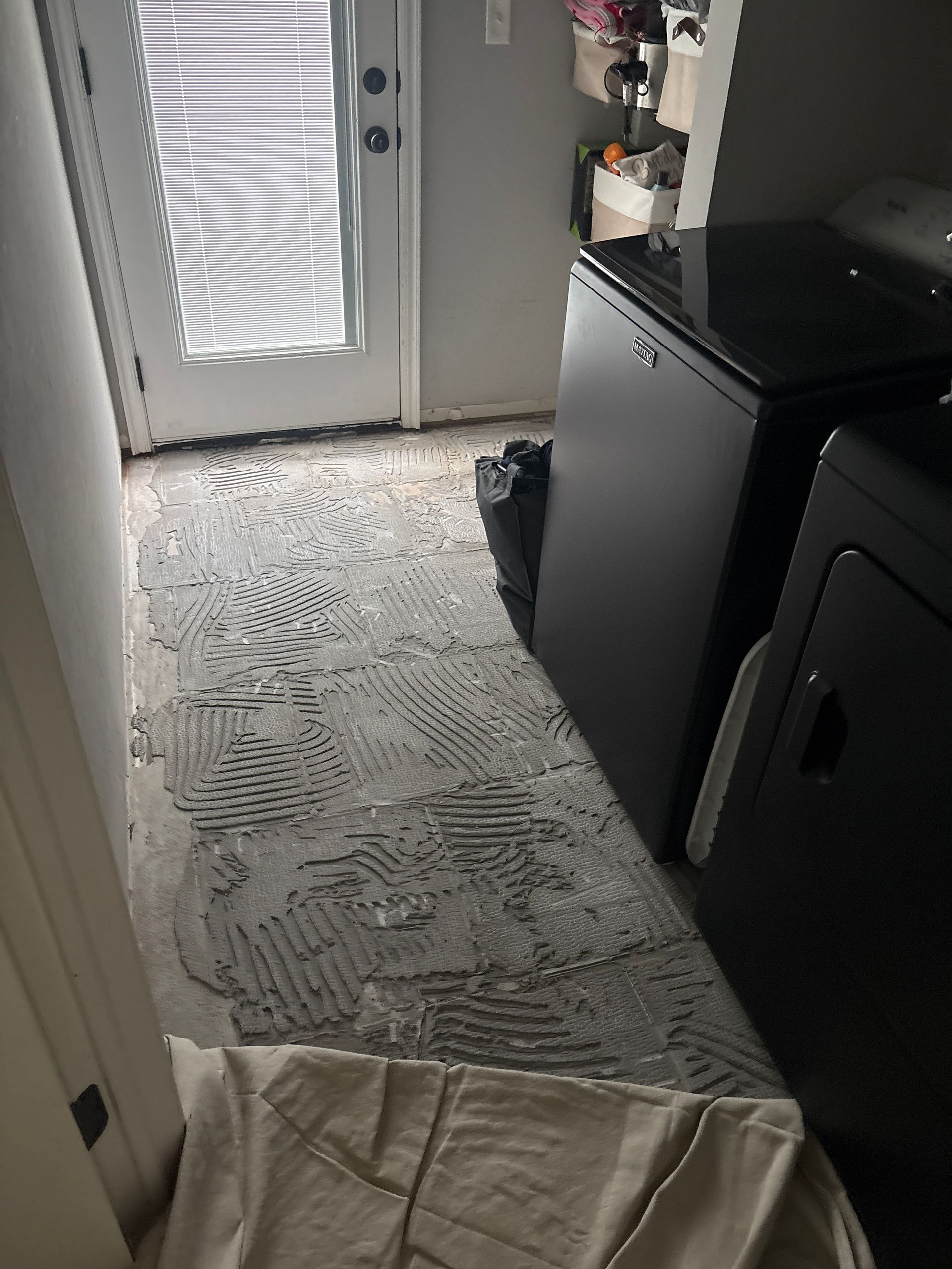 Laundry room with a washer and dryer, patterned rug, and door with blinds letting in light.
